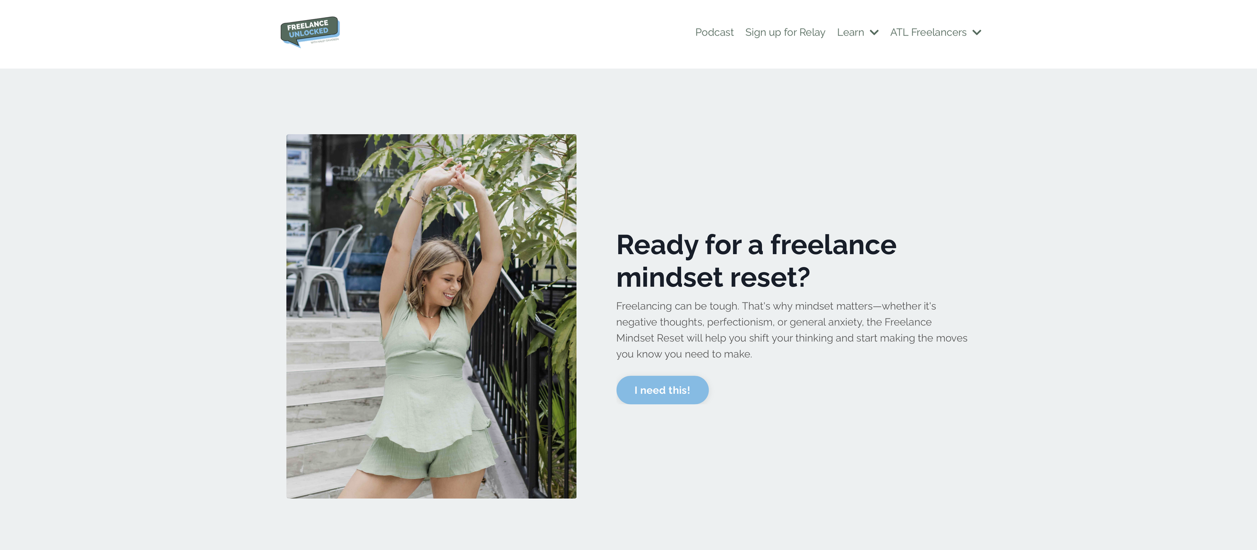 A woman in a light green outfit stretching and smiling outdoors with greenery and stairs around her.