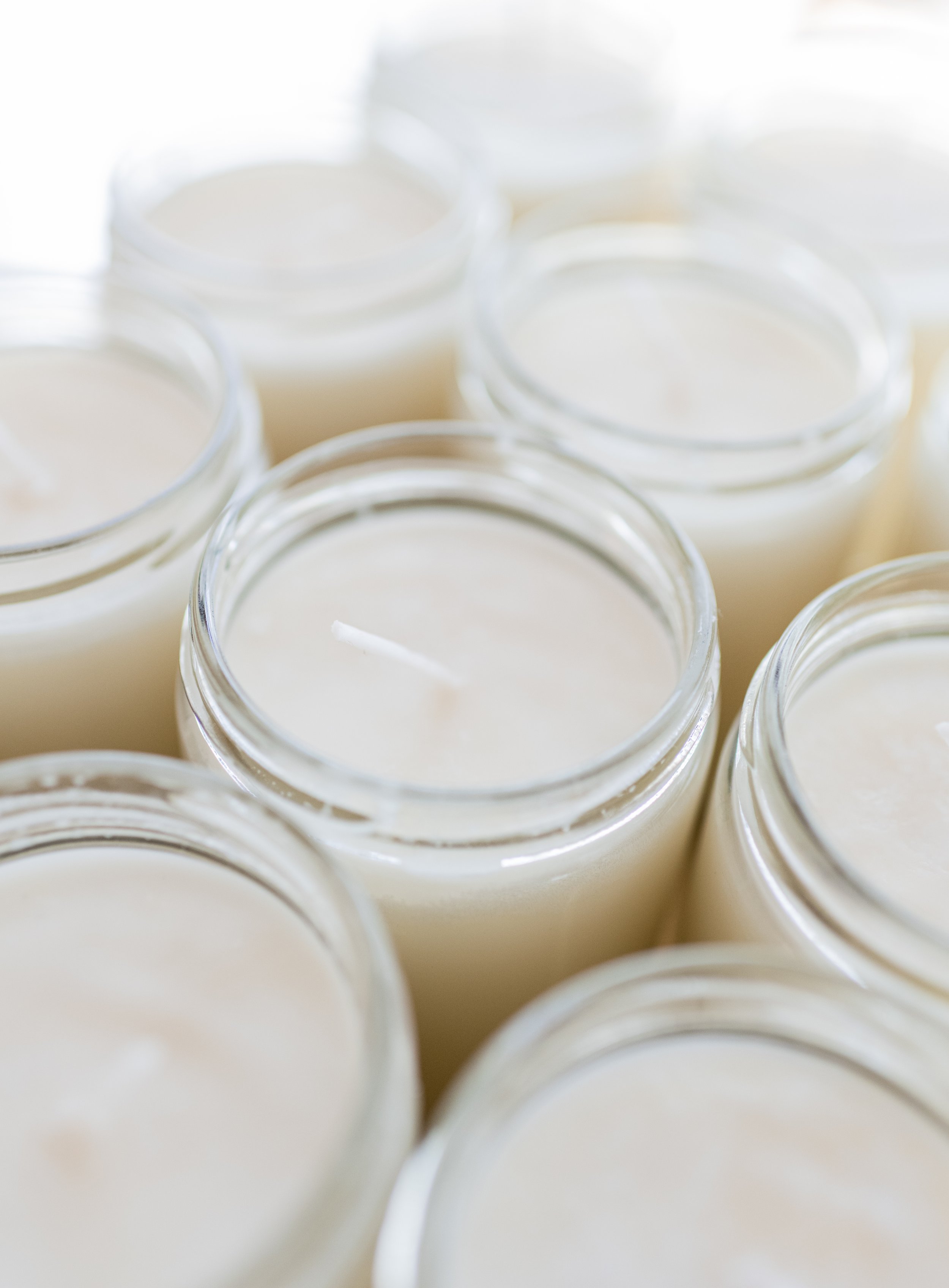 Close-up of multiple white candles in glass jars.