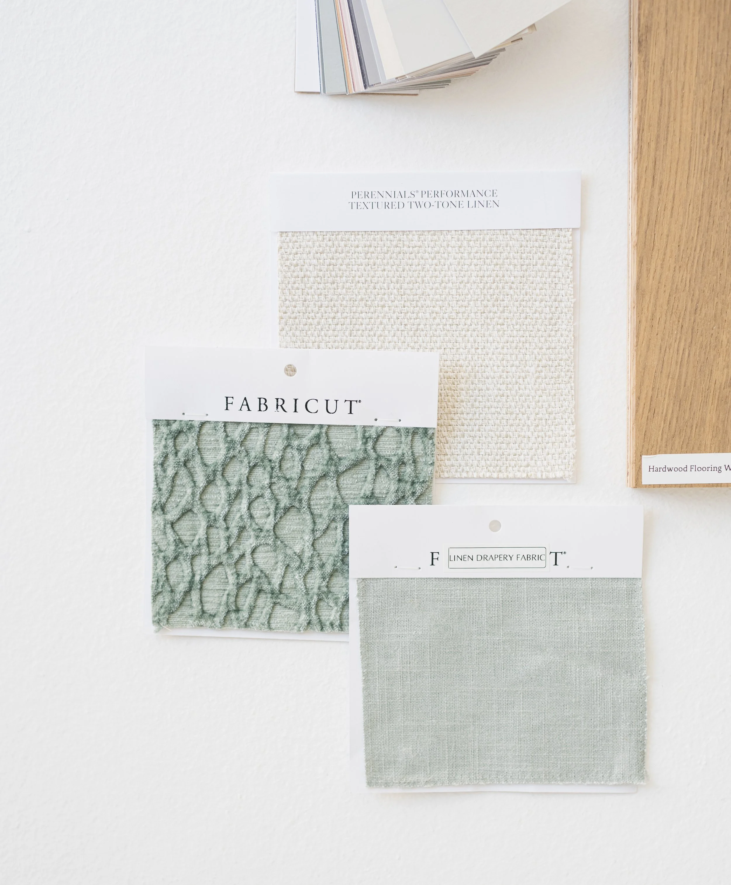 Samples of fabric swatches and paint colors on a wall for interior design.