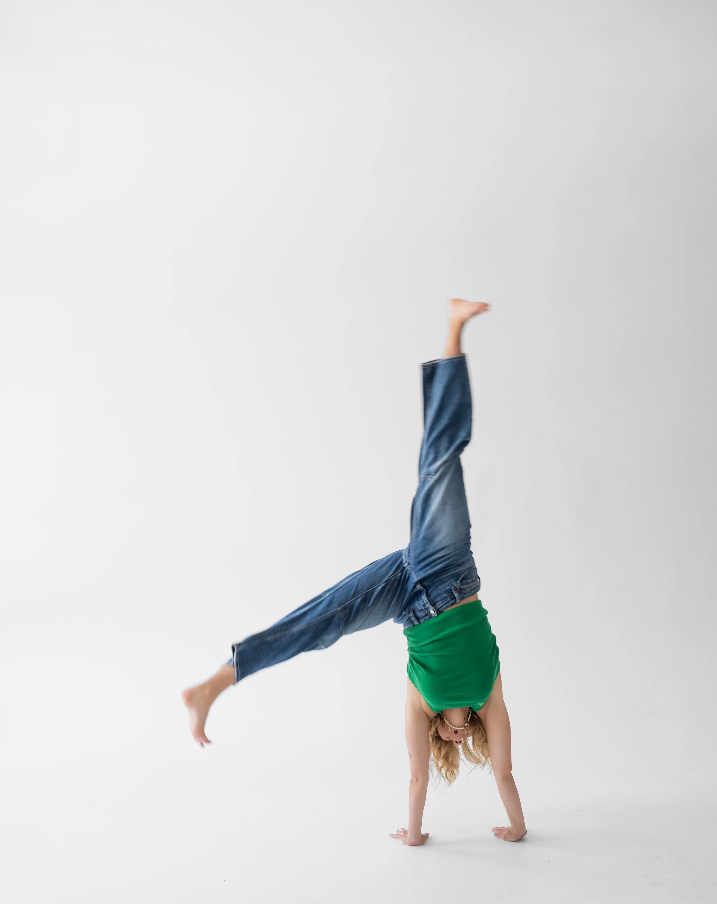 Person performing a handstand with one leg extended upward in a minimal white space.