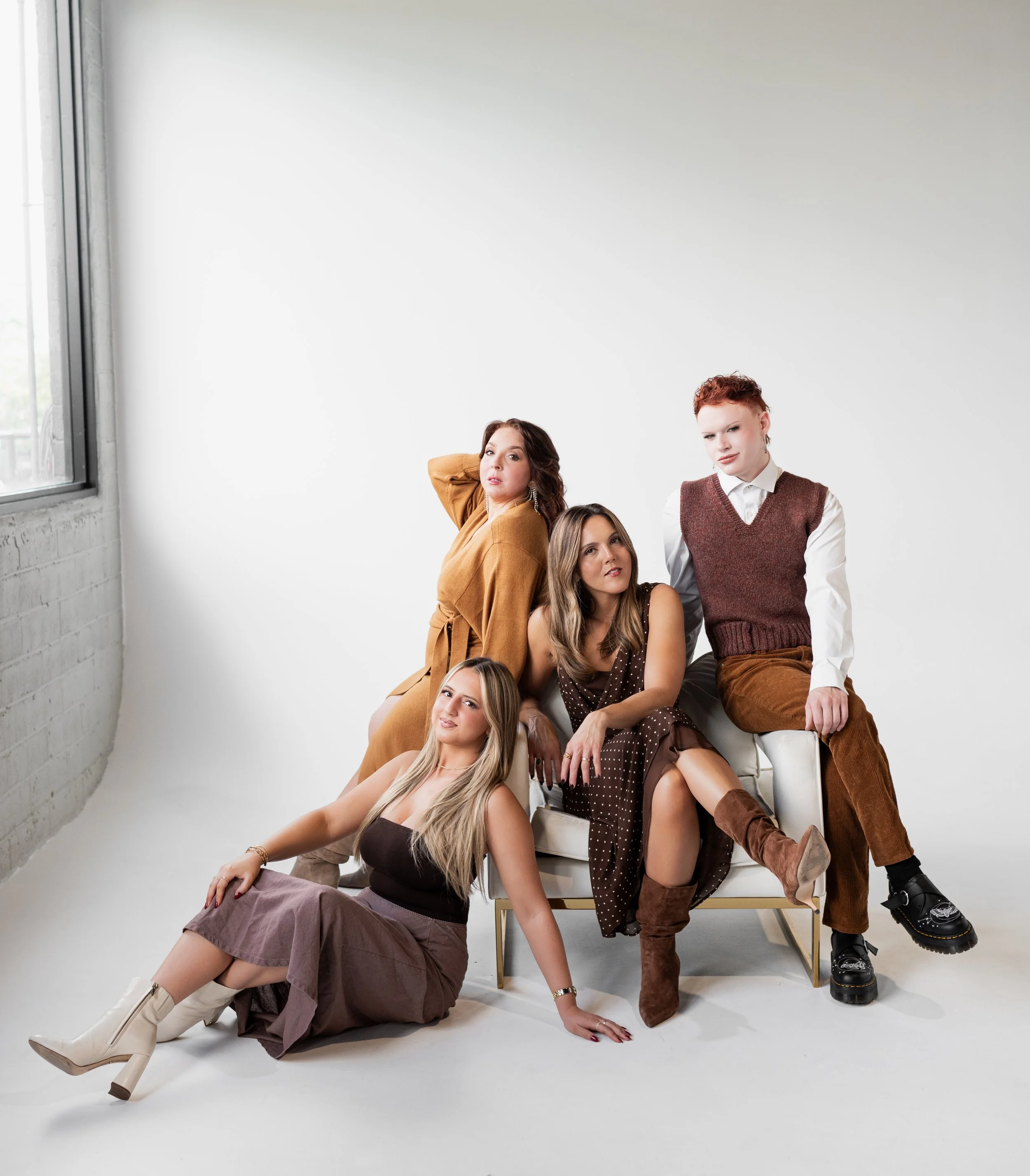 Five women posing together in a studio with a white background, dressed in stylish fall fashion outfits.
