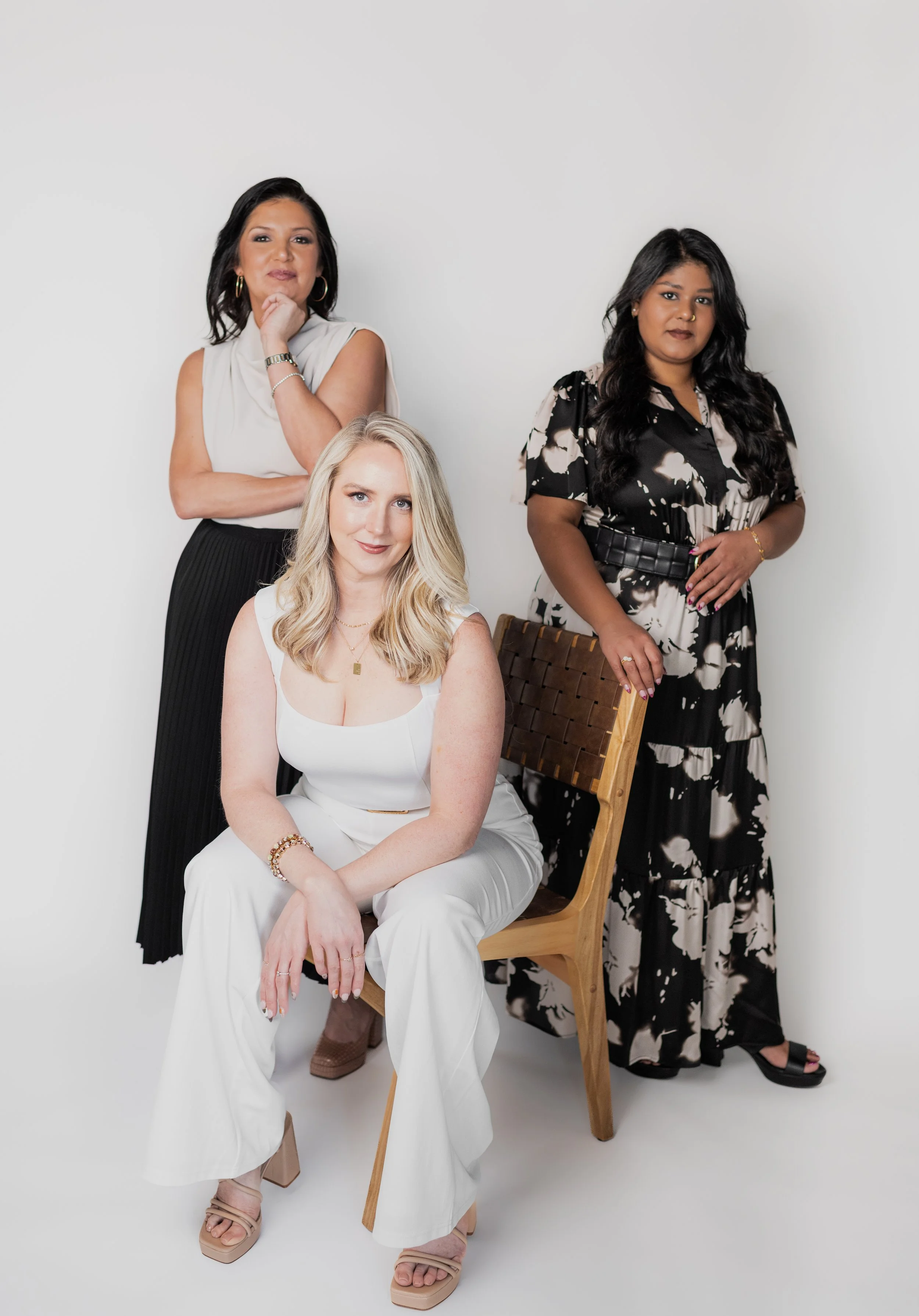 Three women posing together in a studio with a white background.