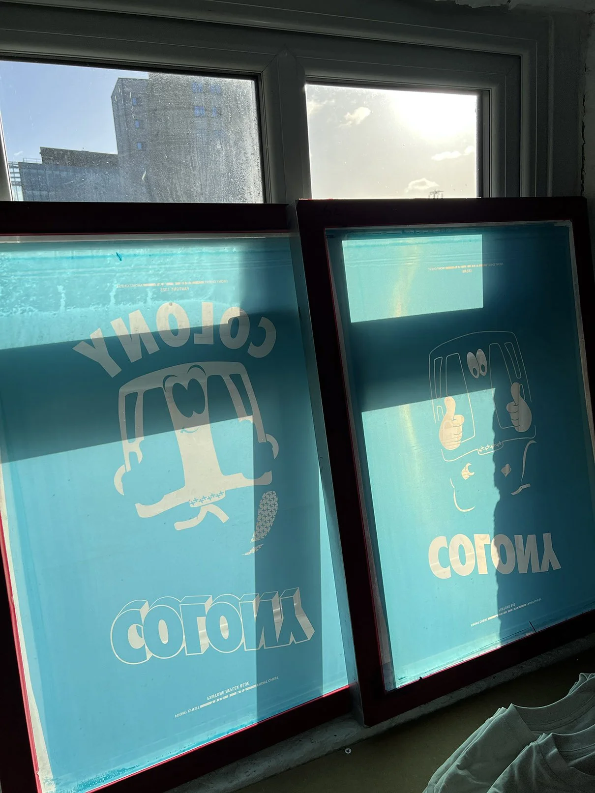 Two exposed silkscreens in with artwork ready to screenprint onto t-shirts.