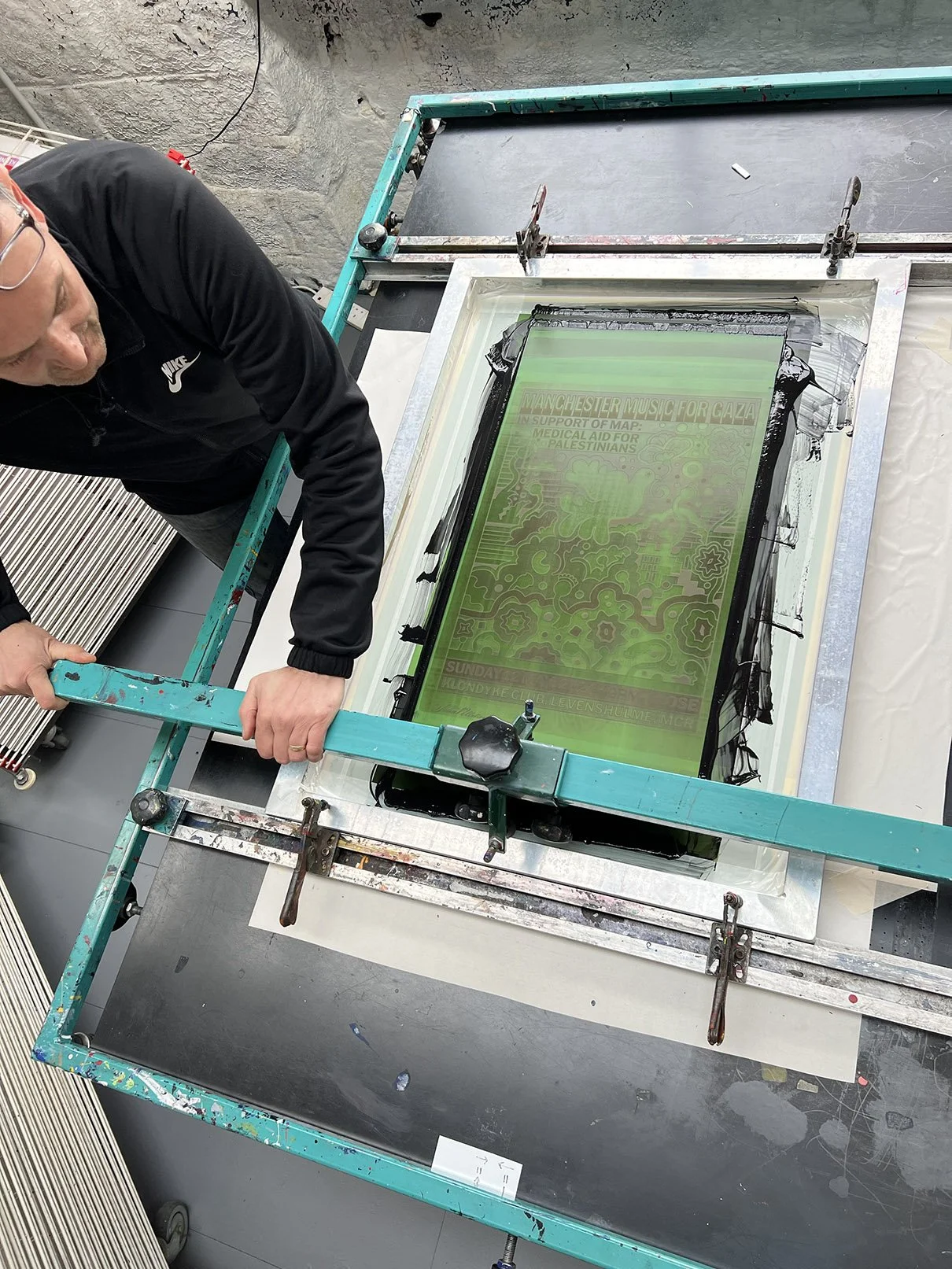 Person working on a stained glass window with a support frame on a work table.