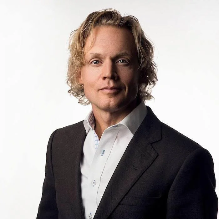 Man i mörk kavaj och vit skjorta mot vit bakgrund