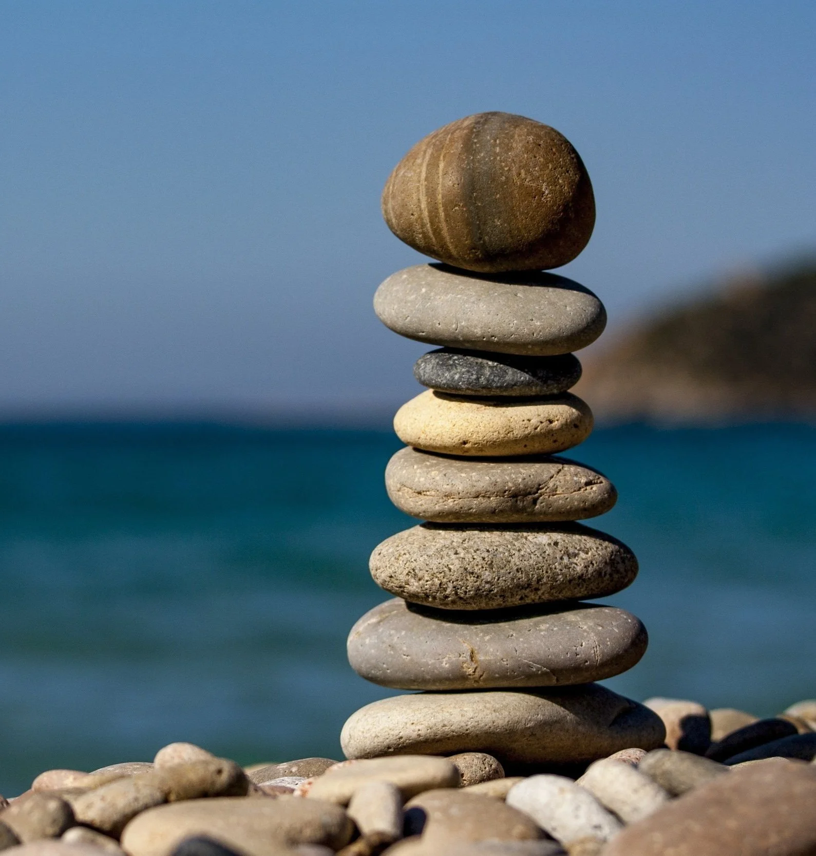 Stenvalv som balanserar på en strand mot havet i bakgrunden.