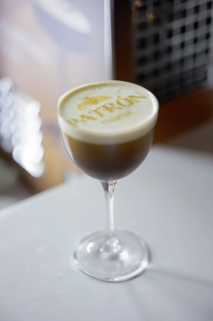 A cocktail in a coupe glass with foam on top, with the word and logo 'Patrón' printed in foam.