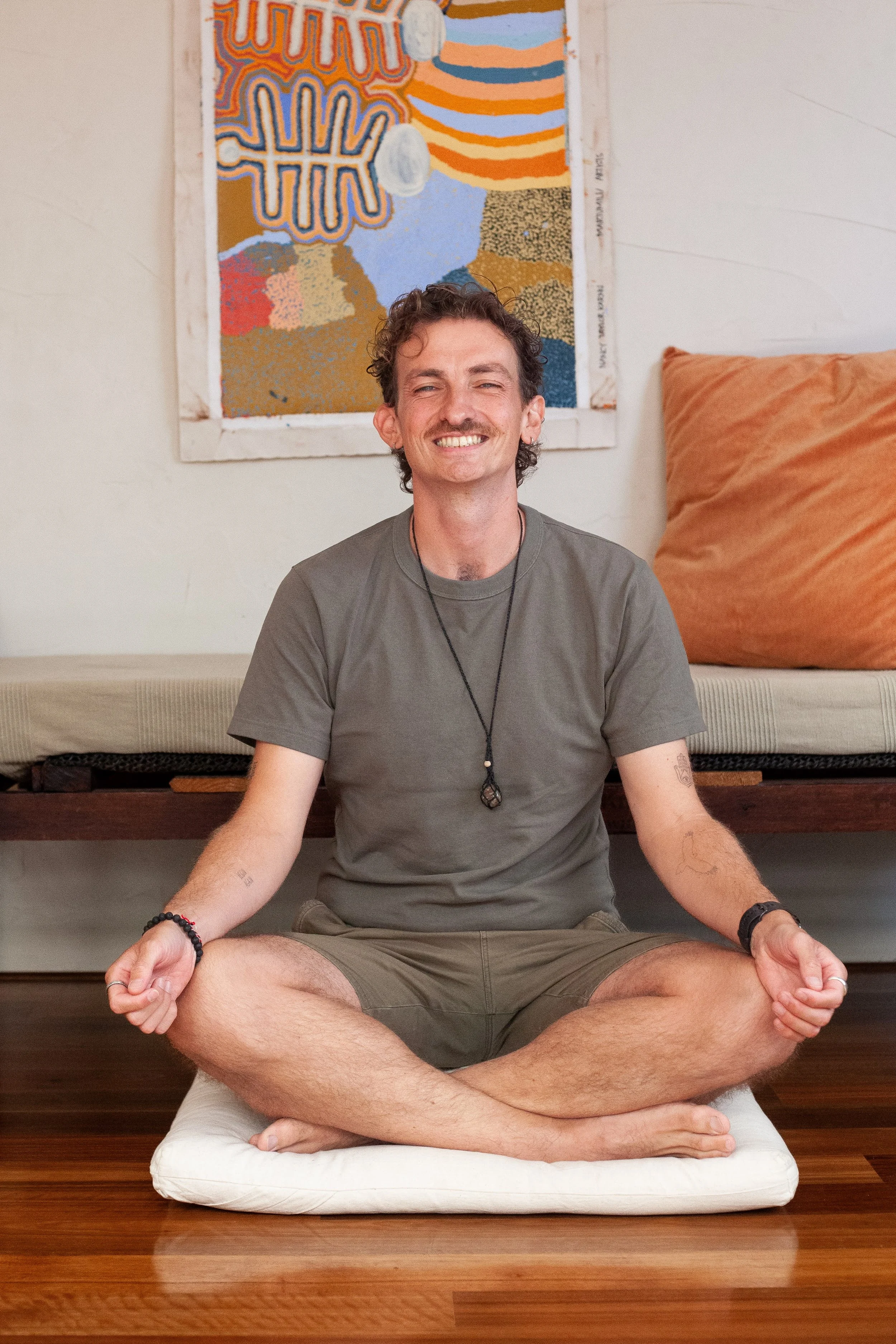 male sitting on cushion, in yoga pose