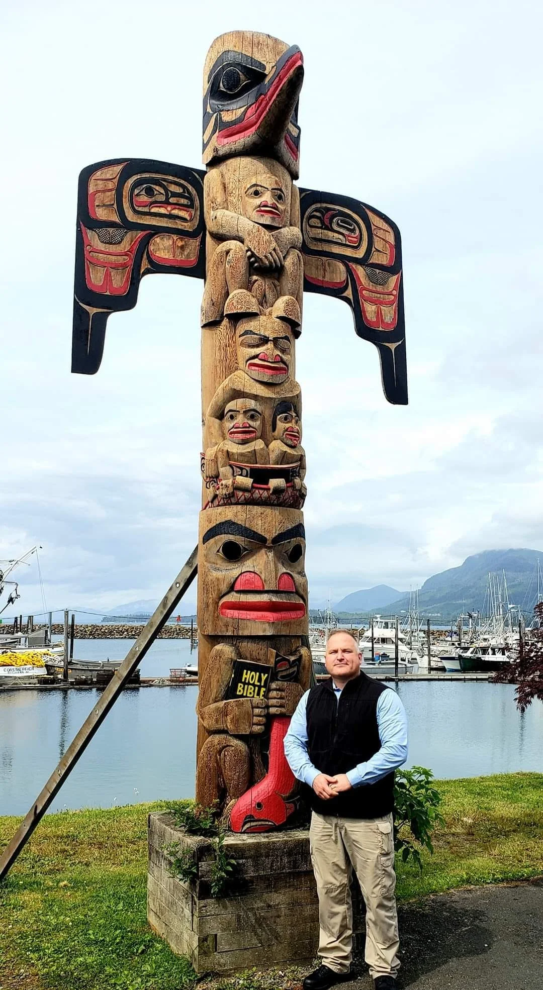 Jerin Falcon standing beside a totem pole in Metlakatla, Alaska.