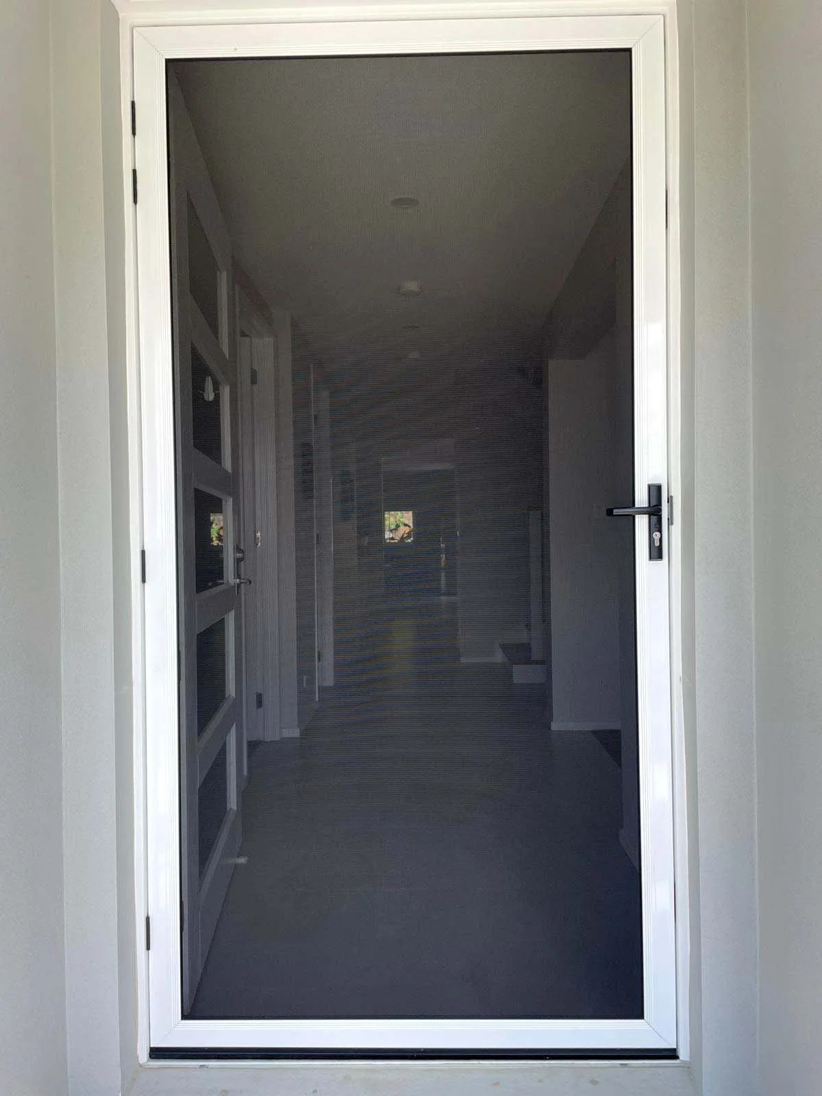Stainless steel security screen front door that opens into a hallway with multiple rooms visible in the background.