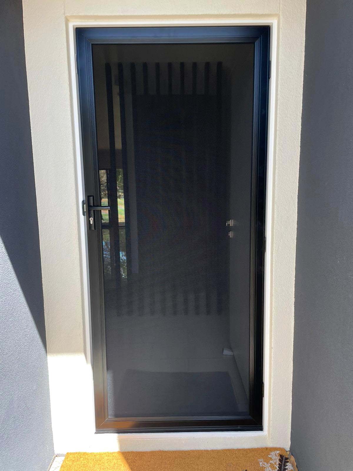 Screenguard stainless steel mesh security door installation with a metal handle set into a rendered wall, leading to an interior space. Located Burleigh Heads.
