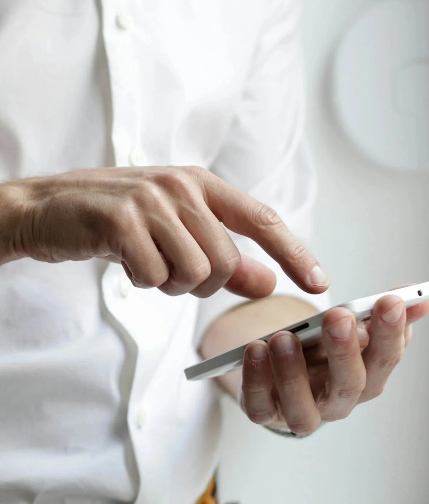 Person in a white shirt using a smartphone, fingers touching the screen. contact us