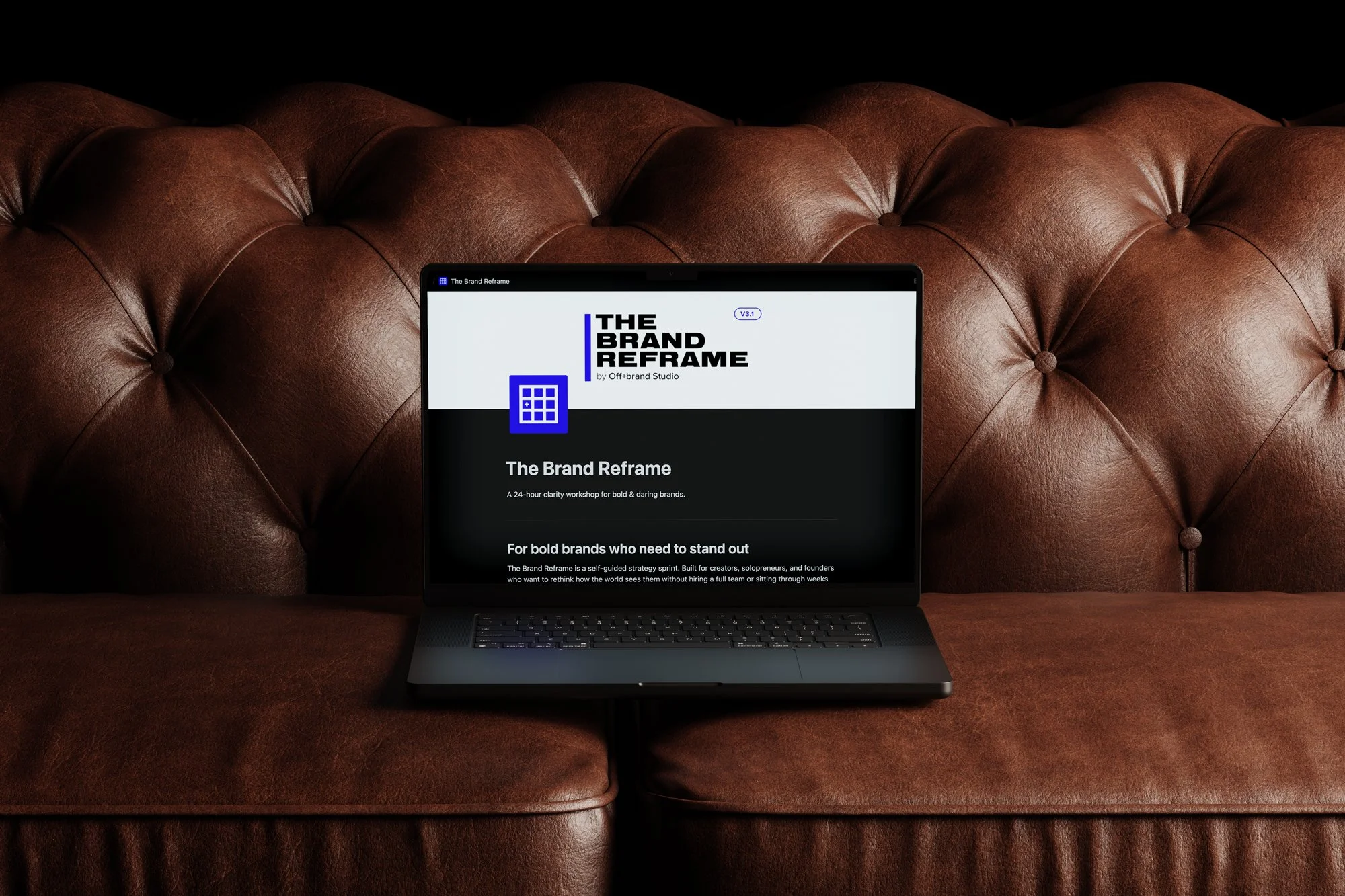 Laptop computer on a brown leather couch displaying a webpage titled 'The Brand Reframe' with a blue icon and black and white text.