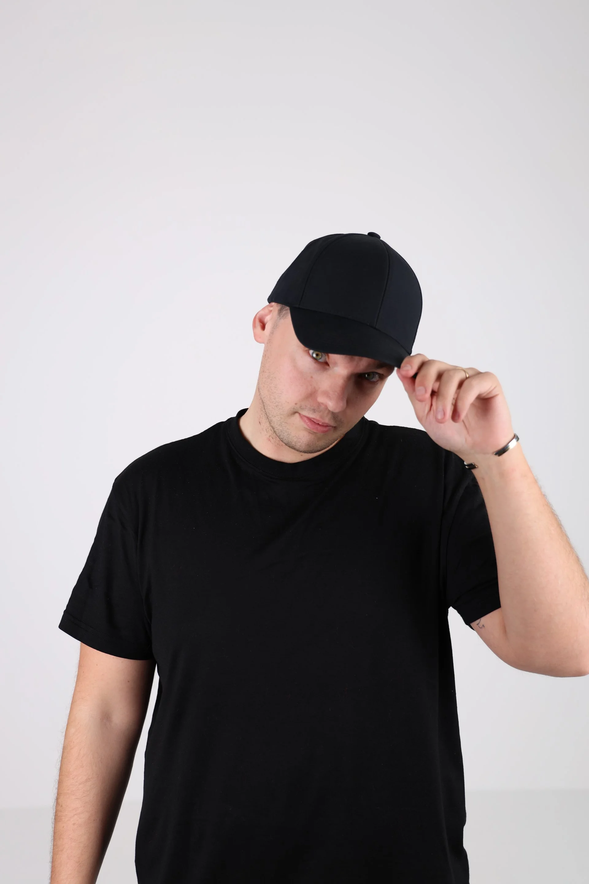 Joakim Falk, the founder and Creative Director of Off+Brand wearing a black t-shirt and black baseball cap, tilting the cap slightly.