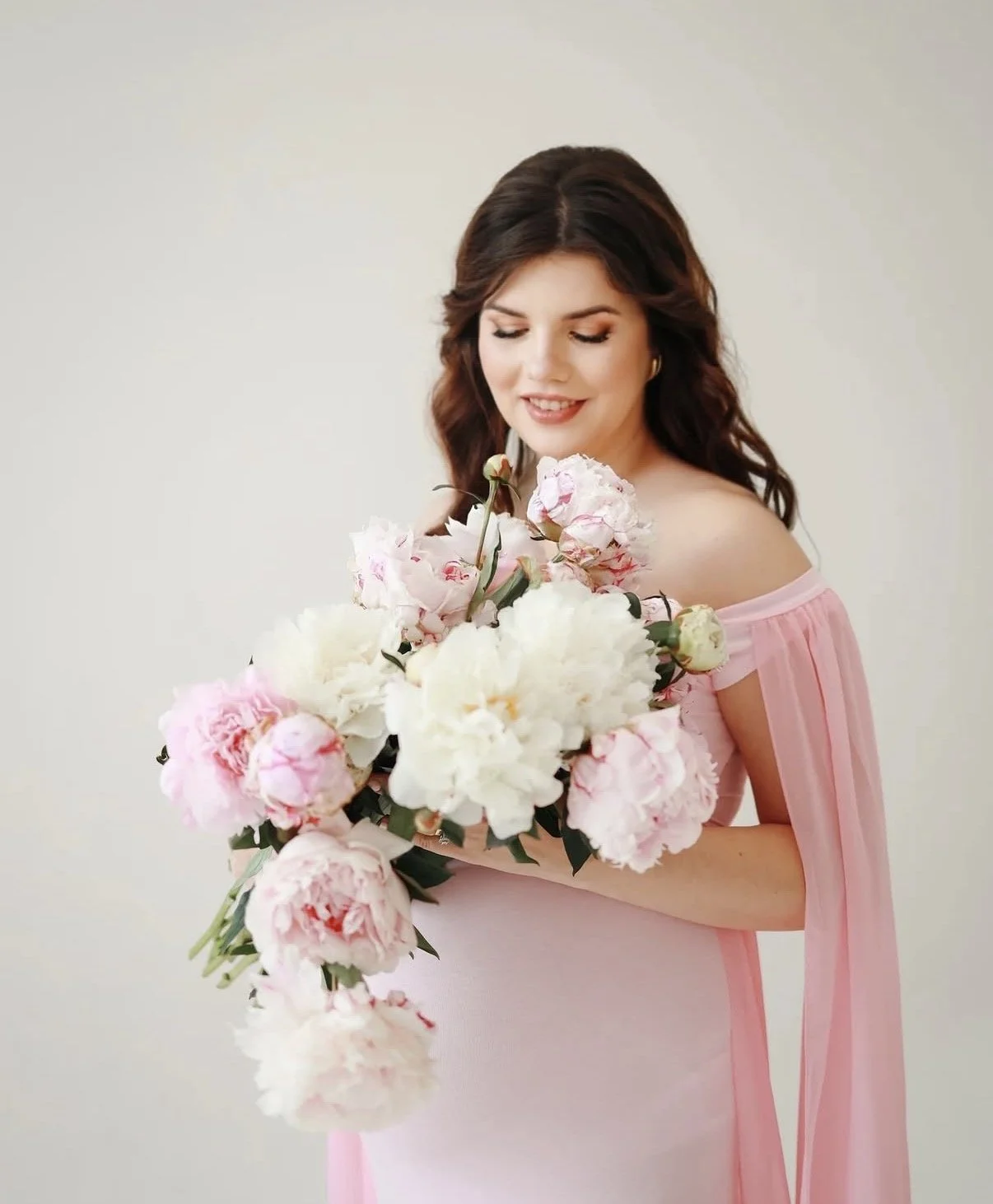 Woman in pink dress holding a bouquet of pink and white flowers.