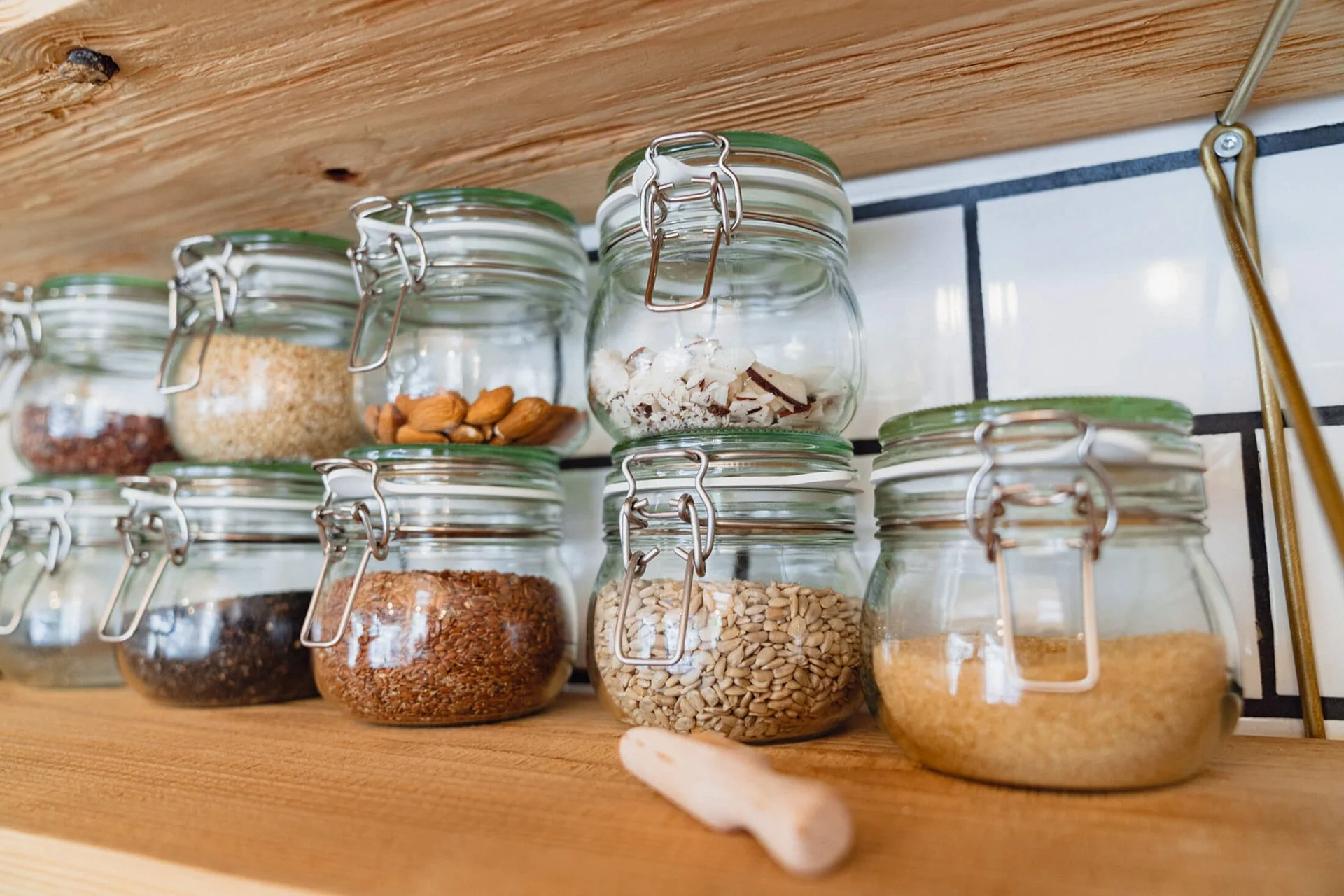 Gläser mit verschiedenen Samen und Nüssen auf einem Holzregal