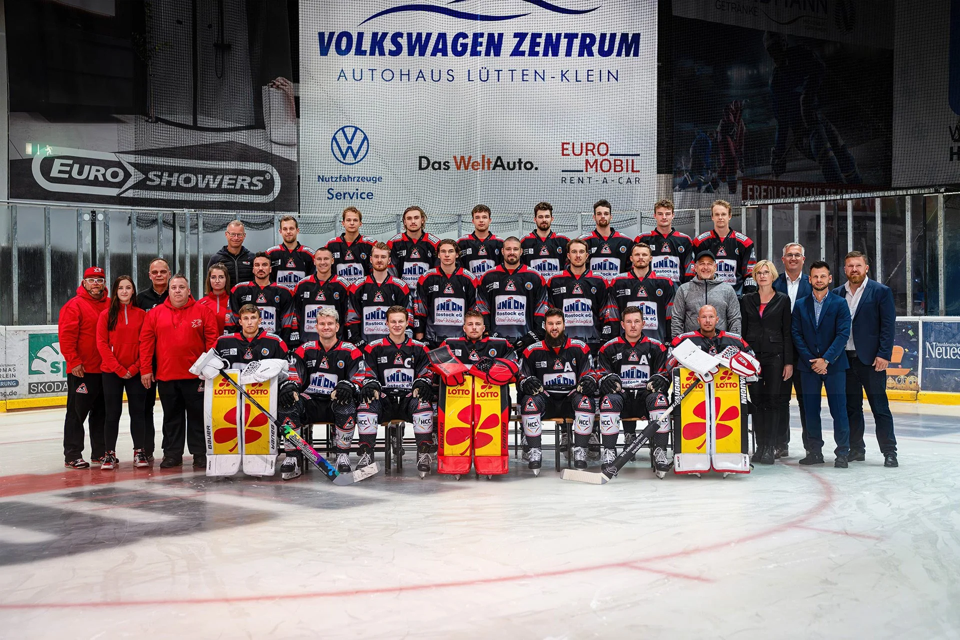 Eishockeyteam mit Trainern und Offiziellen auf dem Eis in einer Eishockeyhalle