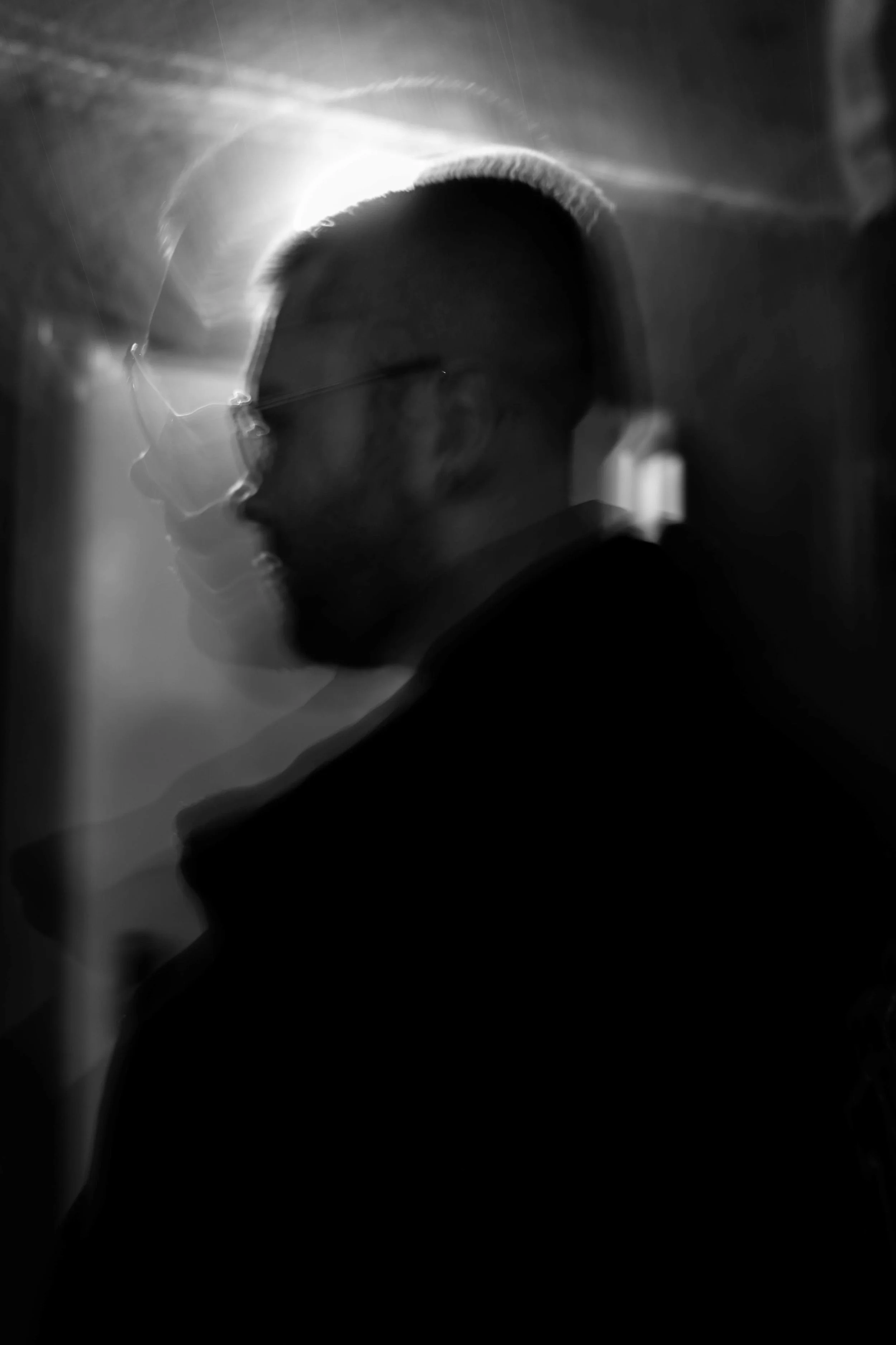 Schwarz-weiß-Fotografie von VAUH mit Brille, seitlicher Profilansicht, verschwommen, mit abstrakten Licht- und Schatteneffekten