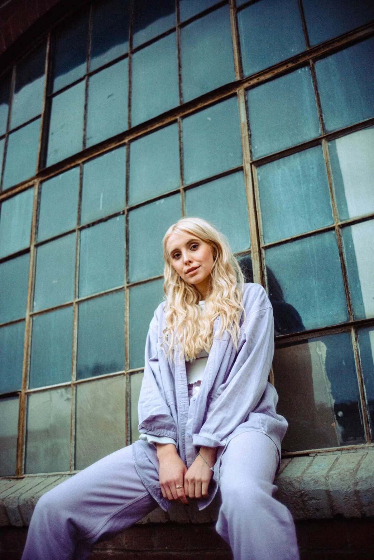 Marijke Smittenaar mit blonden, lockigen Haaren sitzt vor einer großen, alten, blauen Scheibe