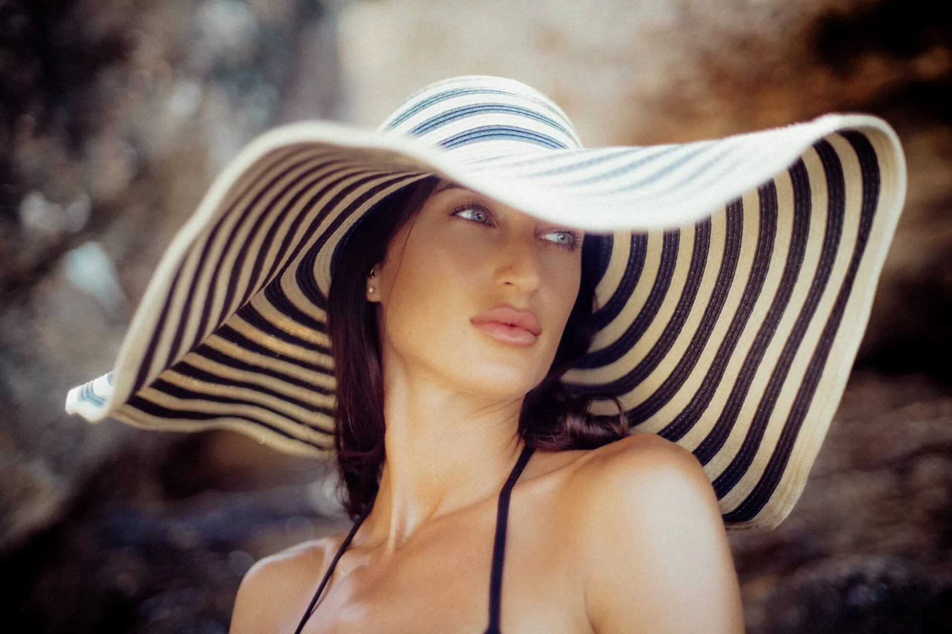 Frau mit großem, gestreiftem Sonnenhut, Blick in die Ferne, Sommer am Strand