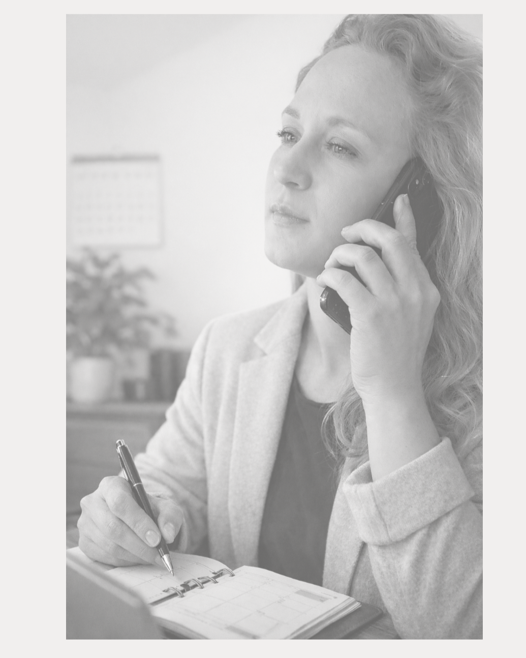 Frau im Büro spricht am Telefon und schreibt in einen Notizblock.