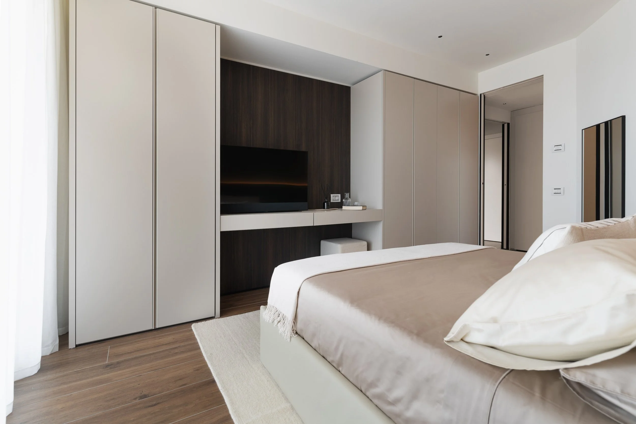 Camera moderna con letto matrimoniale, armadi e televisore a parete.