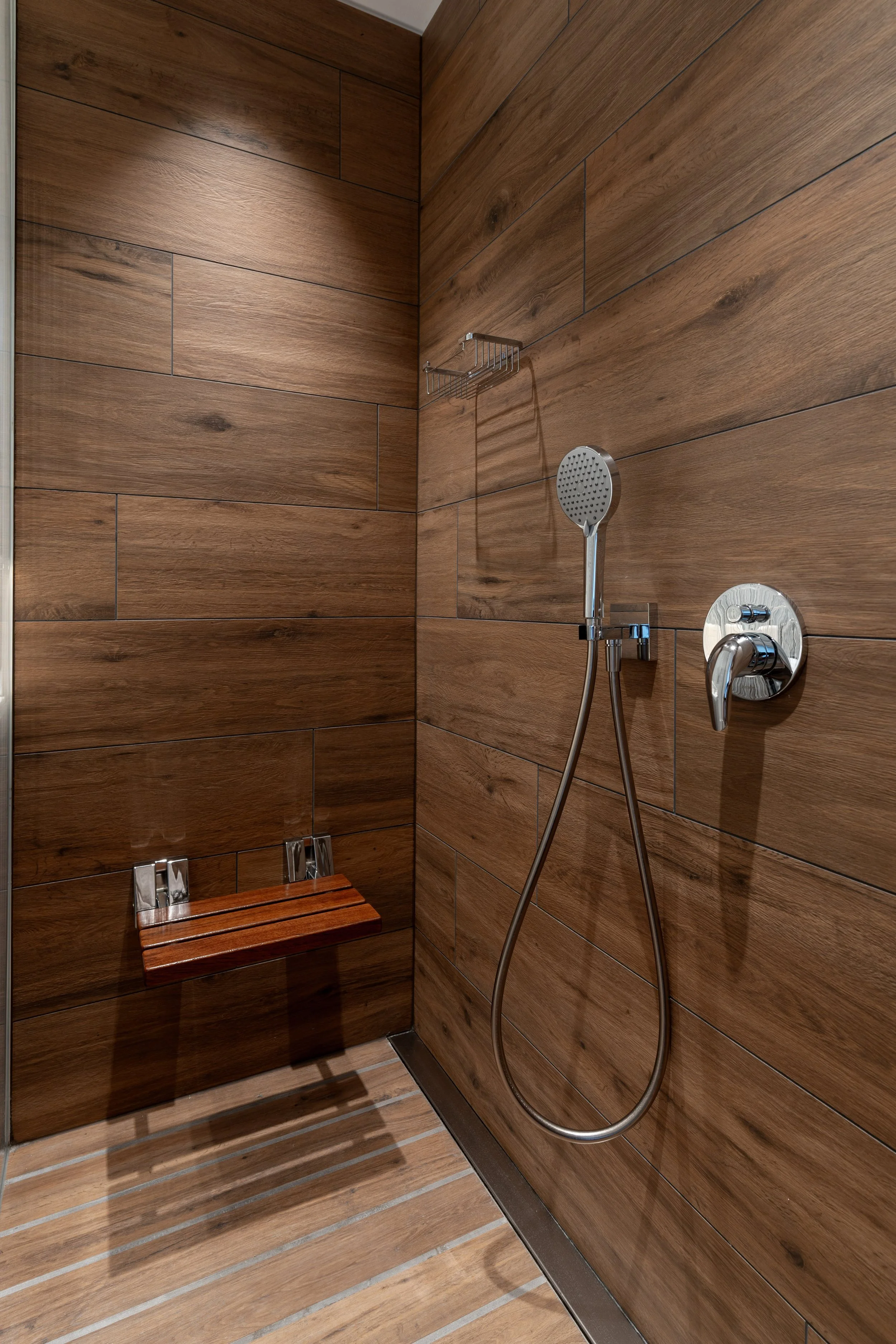 Doccia con pareti rivestite in legno, soffione, monocomando e sedia in legno