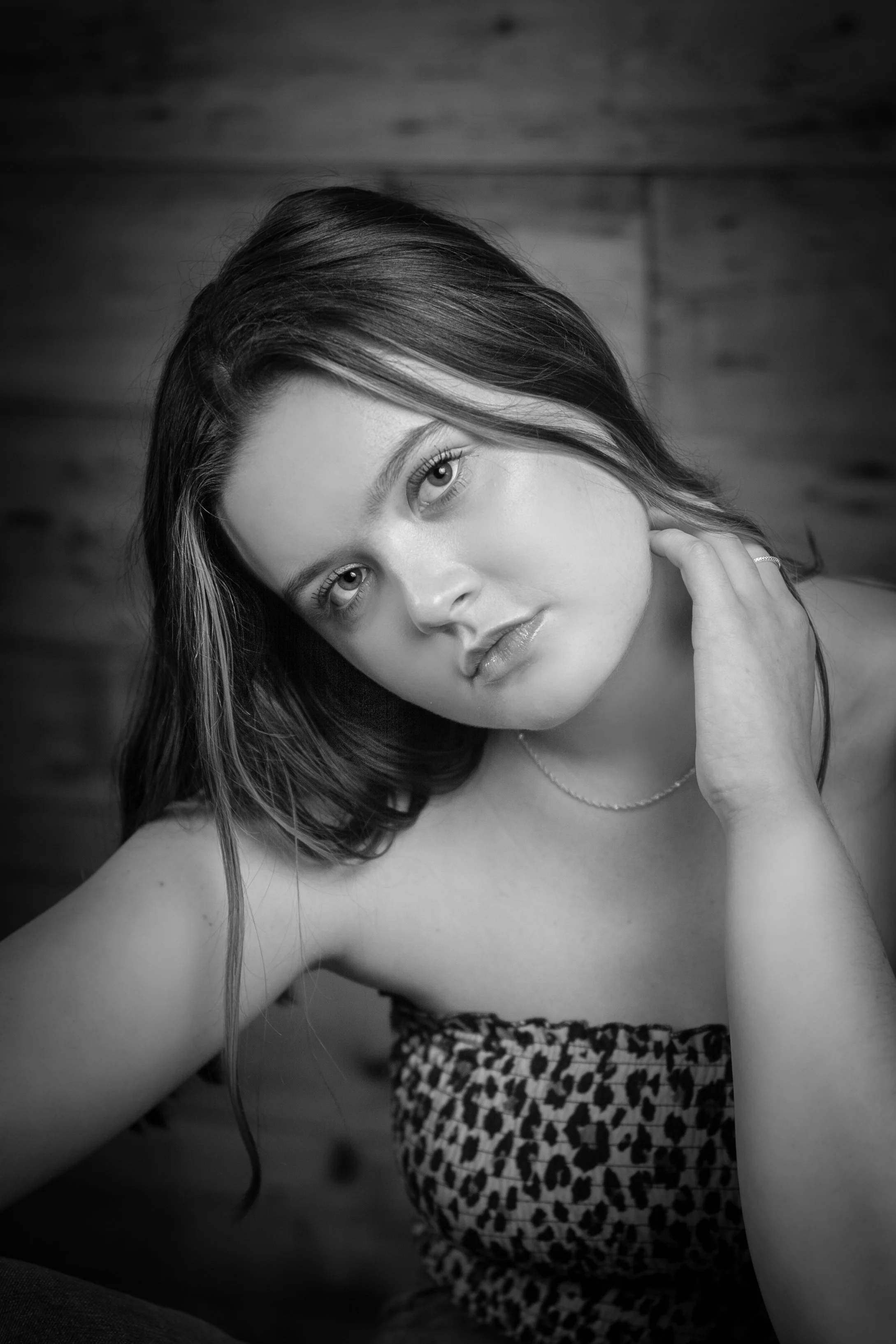 Abi Mack posing with her head tilted with her hand to her neck, image is in black and white.