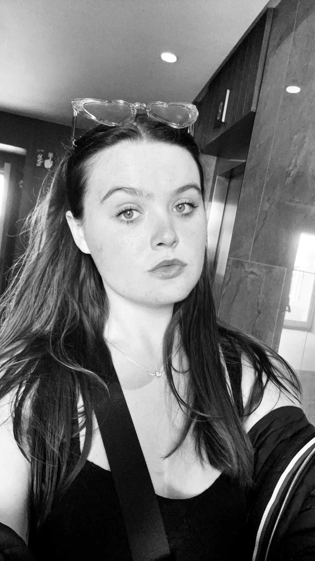 Abi Mack with sunglasses on her head looking sad in the camera, image is in black and white.