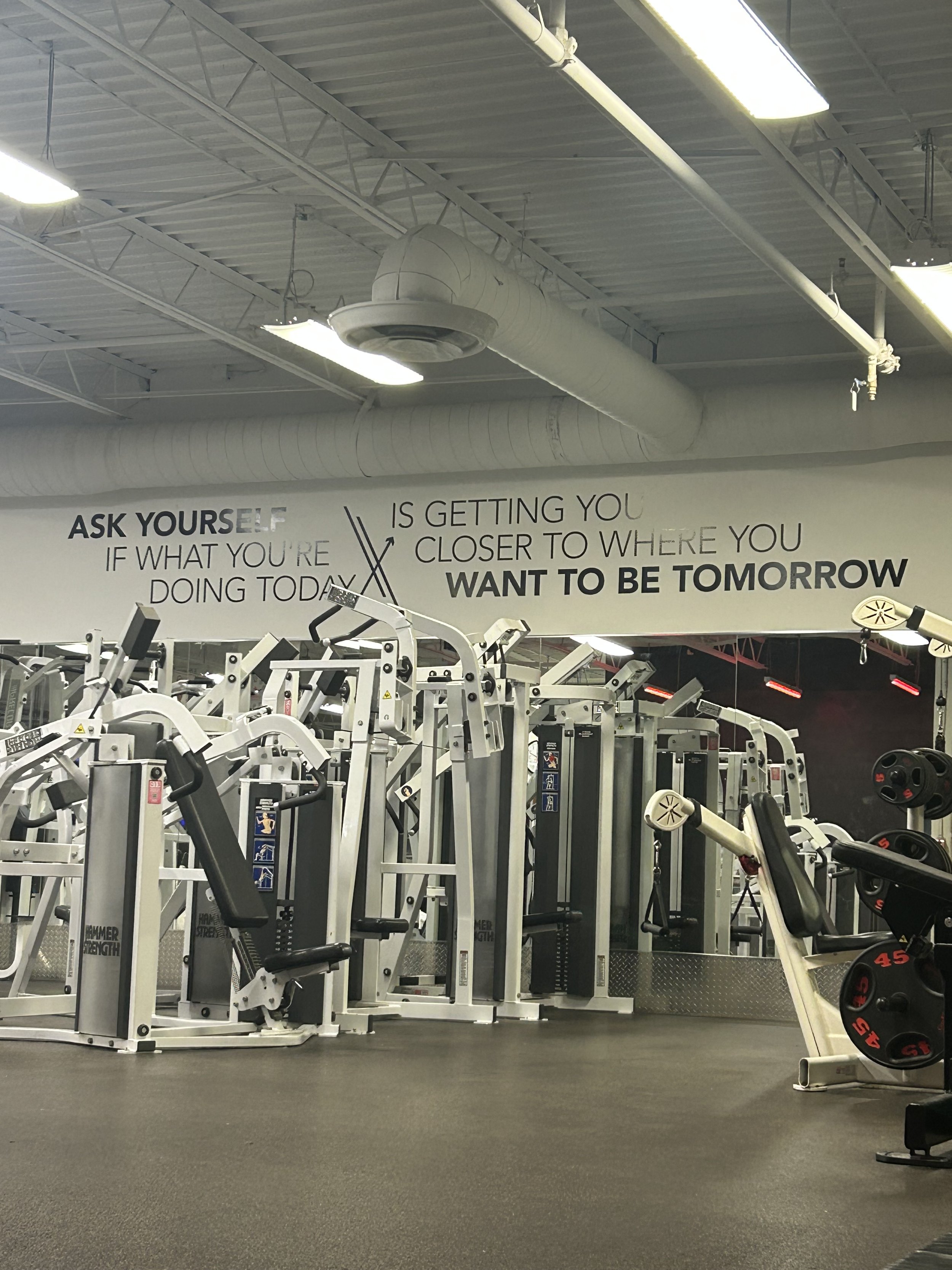 Empty gym with exercise equipment and motivational wall quote.