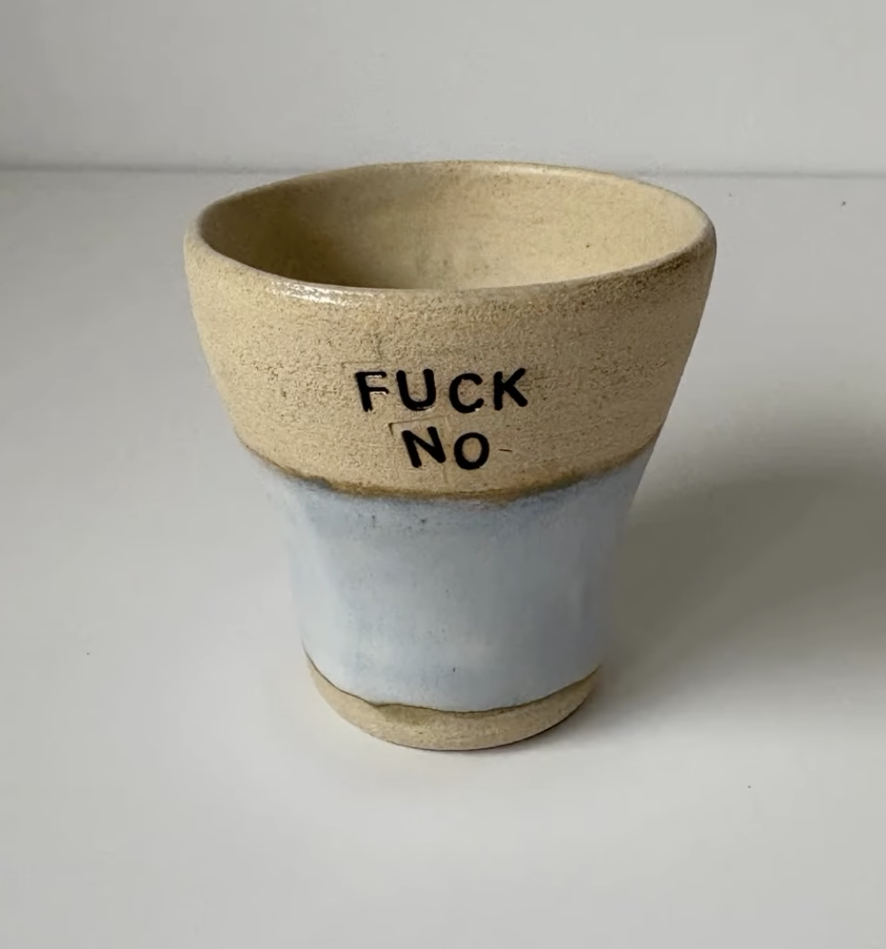 A beige and light blue ceramic cup with the words 'FUCK NO' written on it.