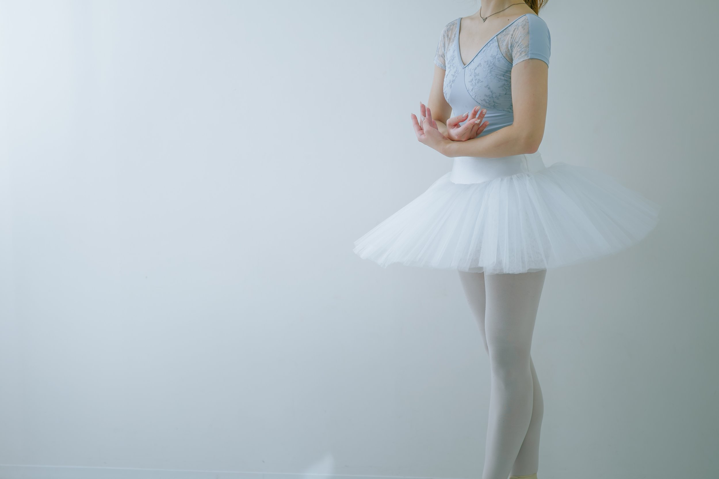 白いチュチュスカートをはいたバレリーナの姿。上半身は淡い青色のバレエ衣装を着ている。背景は白でシンプル。
