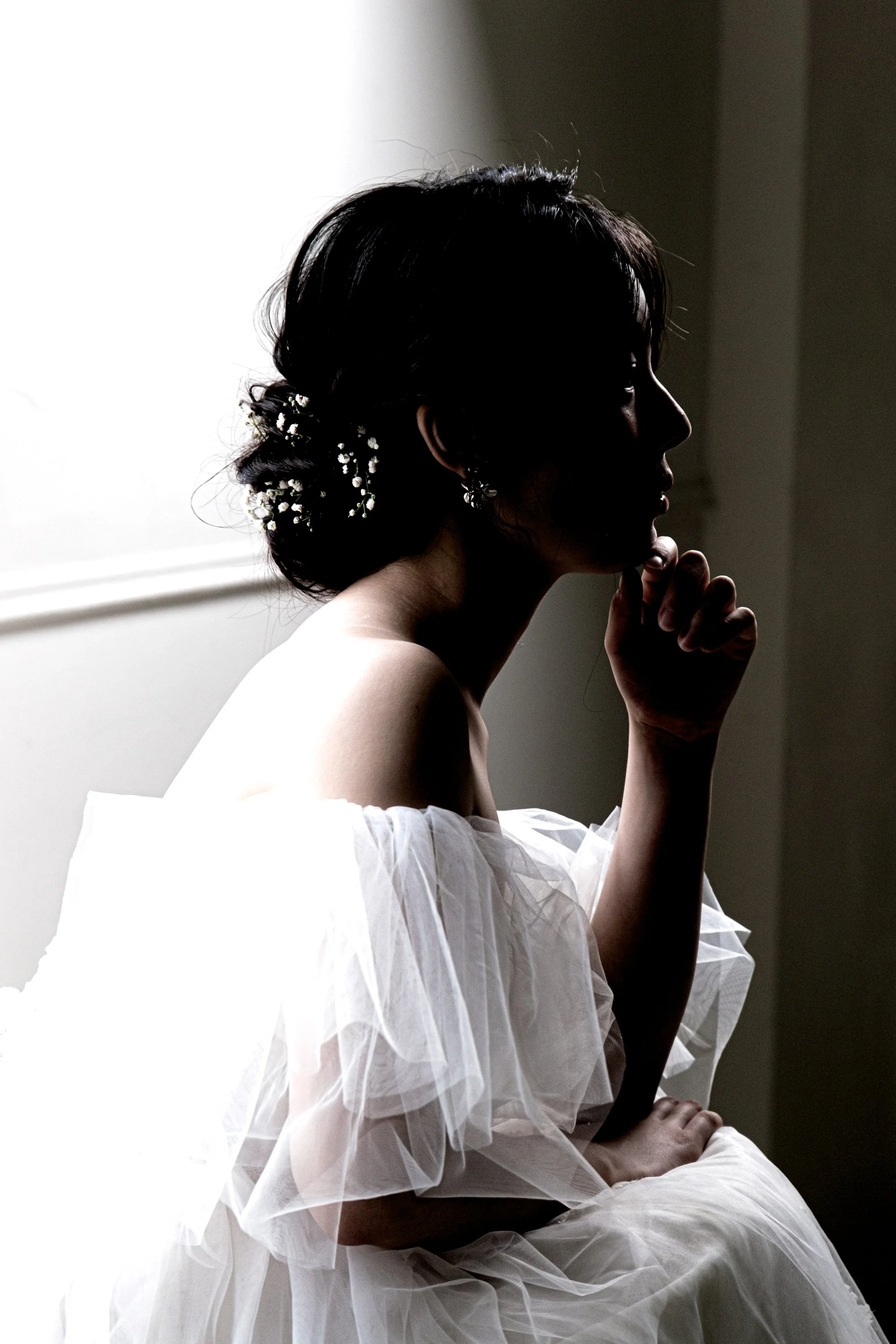 白いドレスを着た女性のシルエット、側面からのポーズ、自然光で背後に明るい窓がある