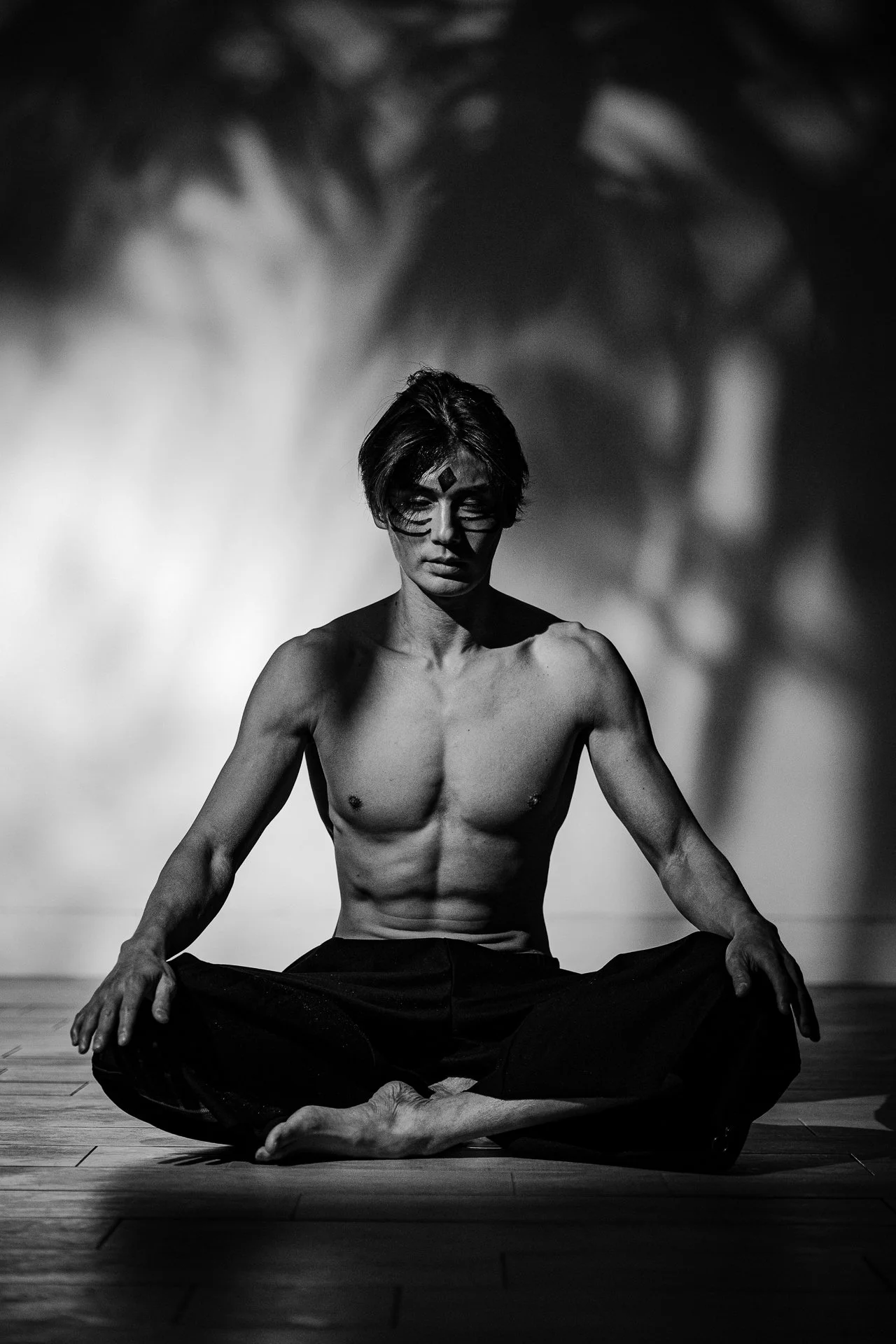 シャツを着ていない男性が座禅を組んでいるシルエットの写真