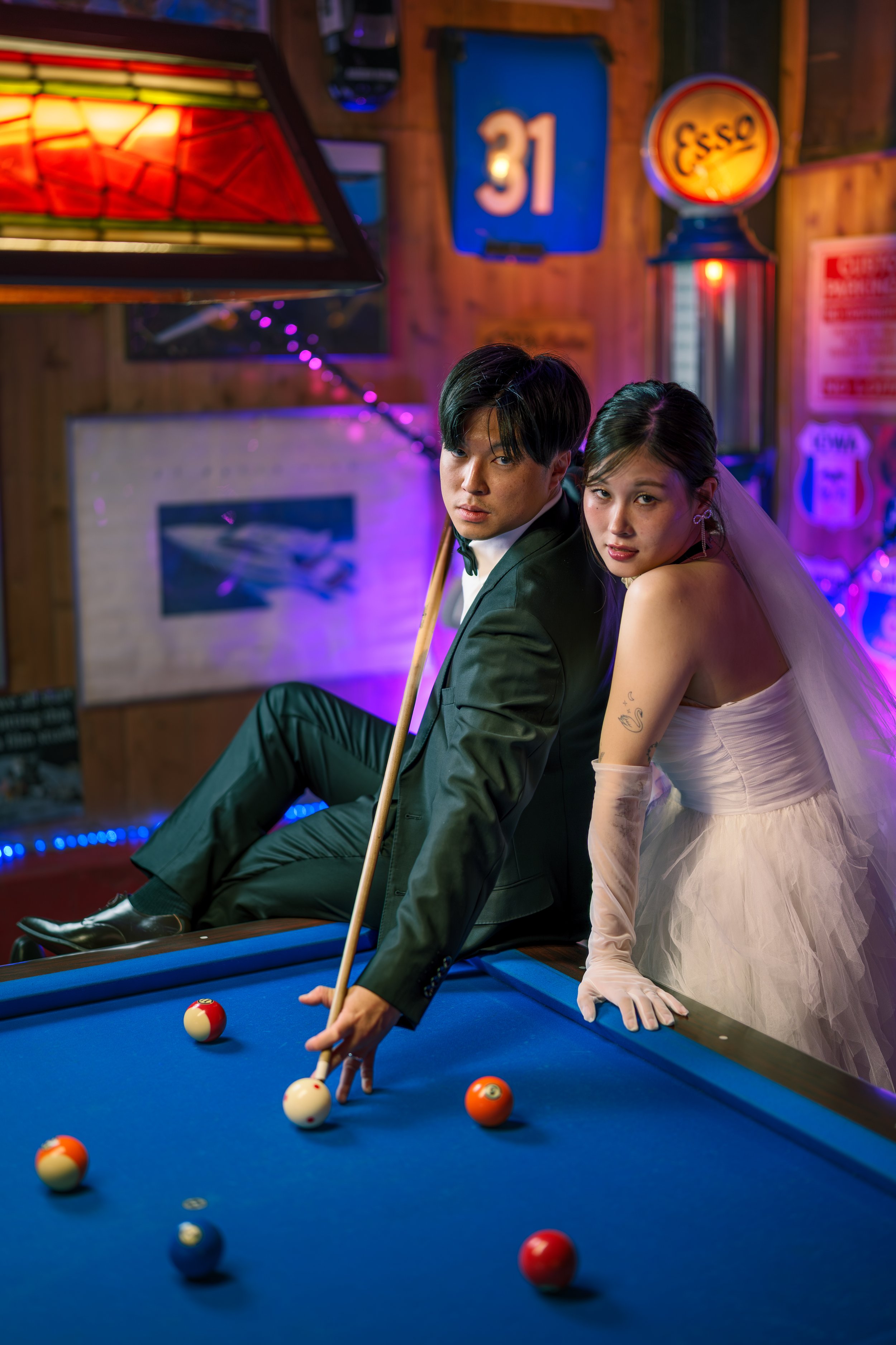 スーツ姿の男性とドレス姿の女性がビリヤード台のそばにいる。背景はレトロなバーのインテリア。