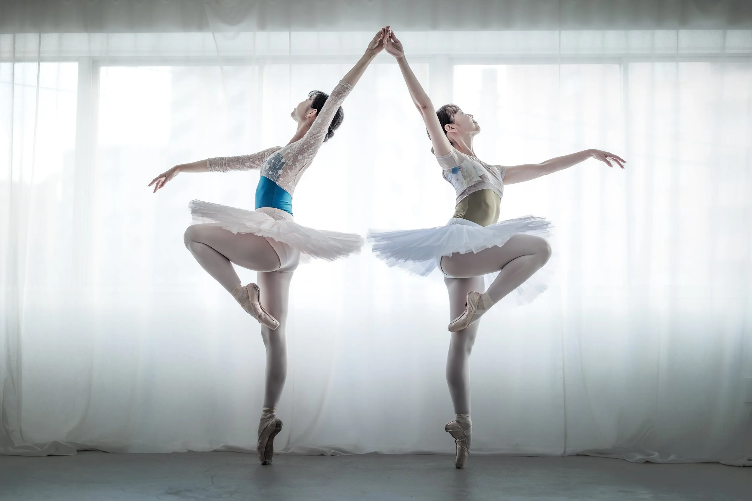 バレエを踊る女性二人が背中合わせでジャンプしている