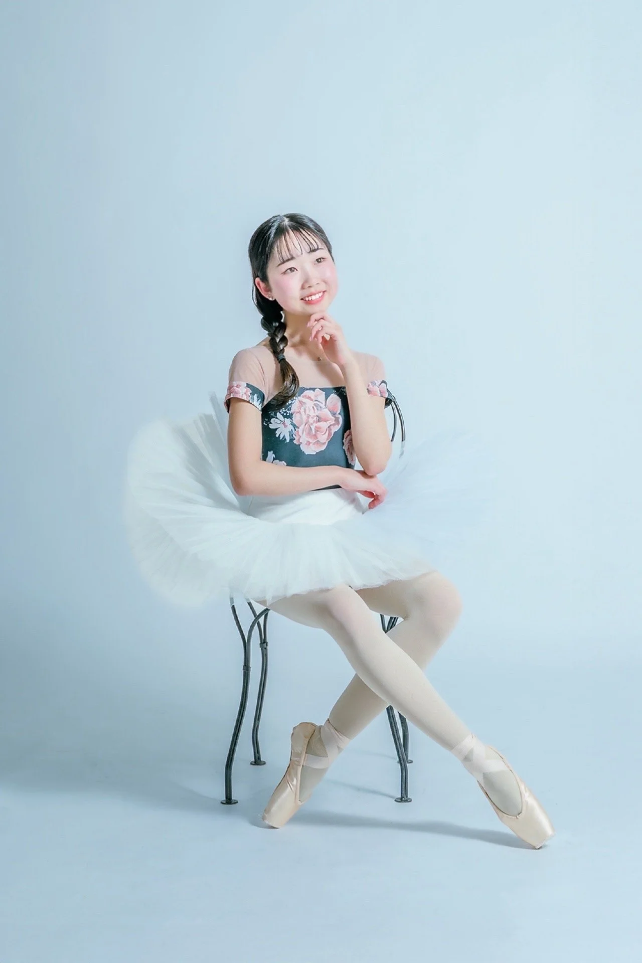 バレエの衣装を着た若い女性が椅子に座って微笑んでいる。