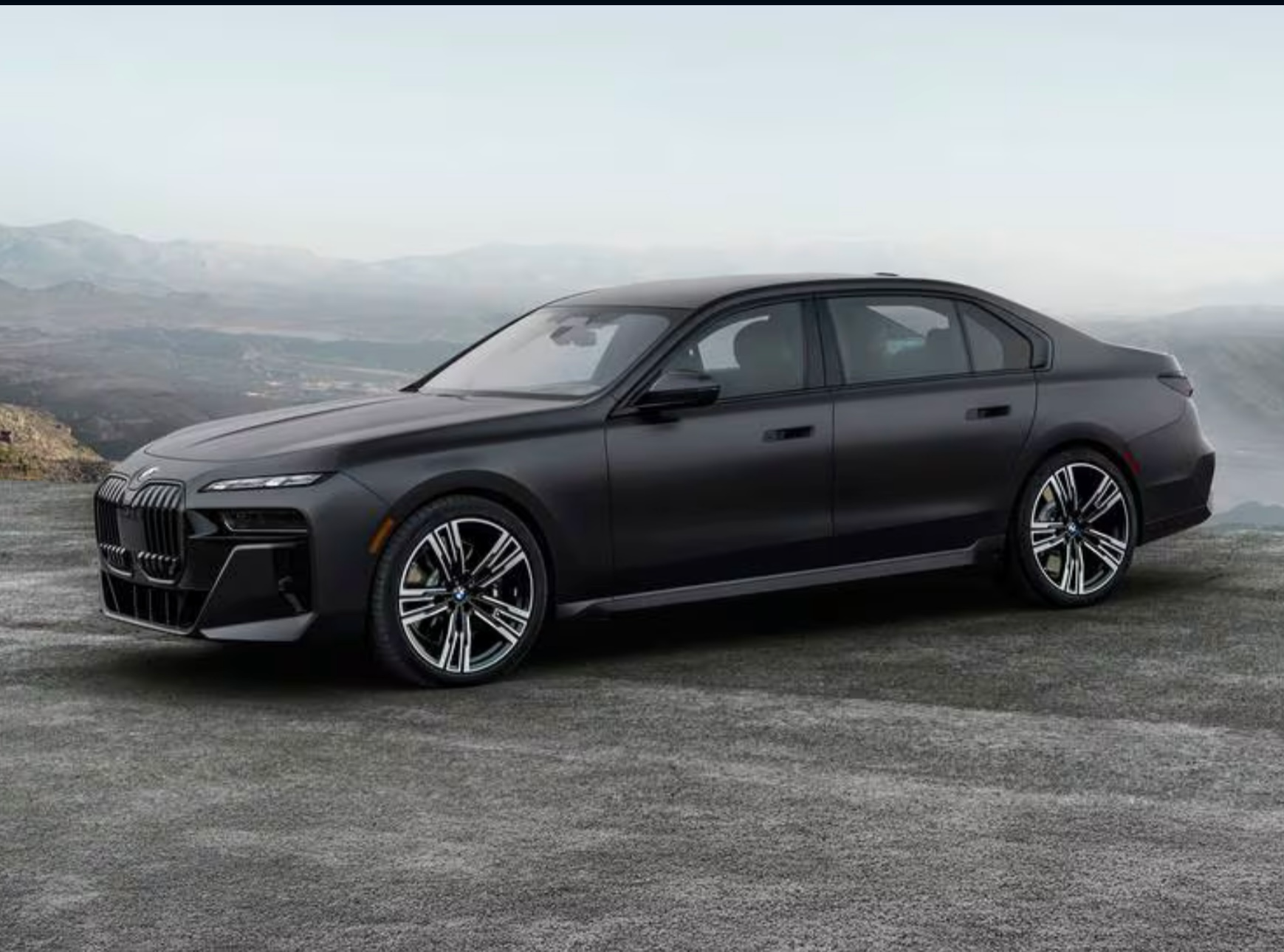 A black luxury sedan car parked on a mountain road with a scenic mountainous background.