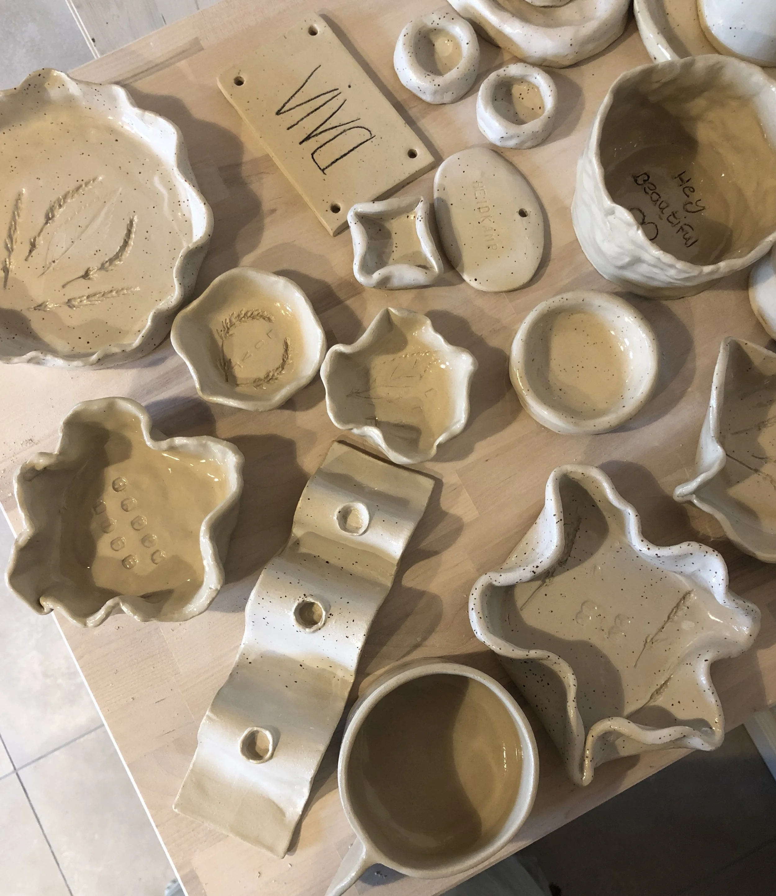 Verschiedene handgefertigte unglasierten Keramikschalen und Dekorationsstücke auf einem Holztisch.