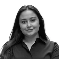 A woman with long dark hair wearing a black shirt, smiling slightly, against a plain white background.