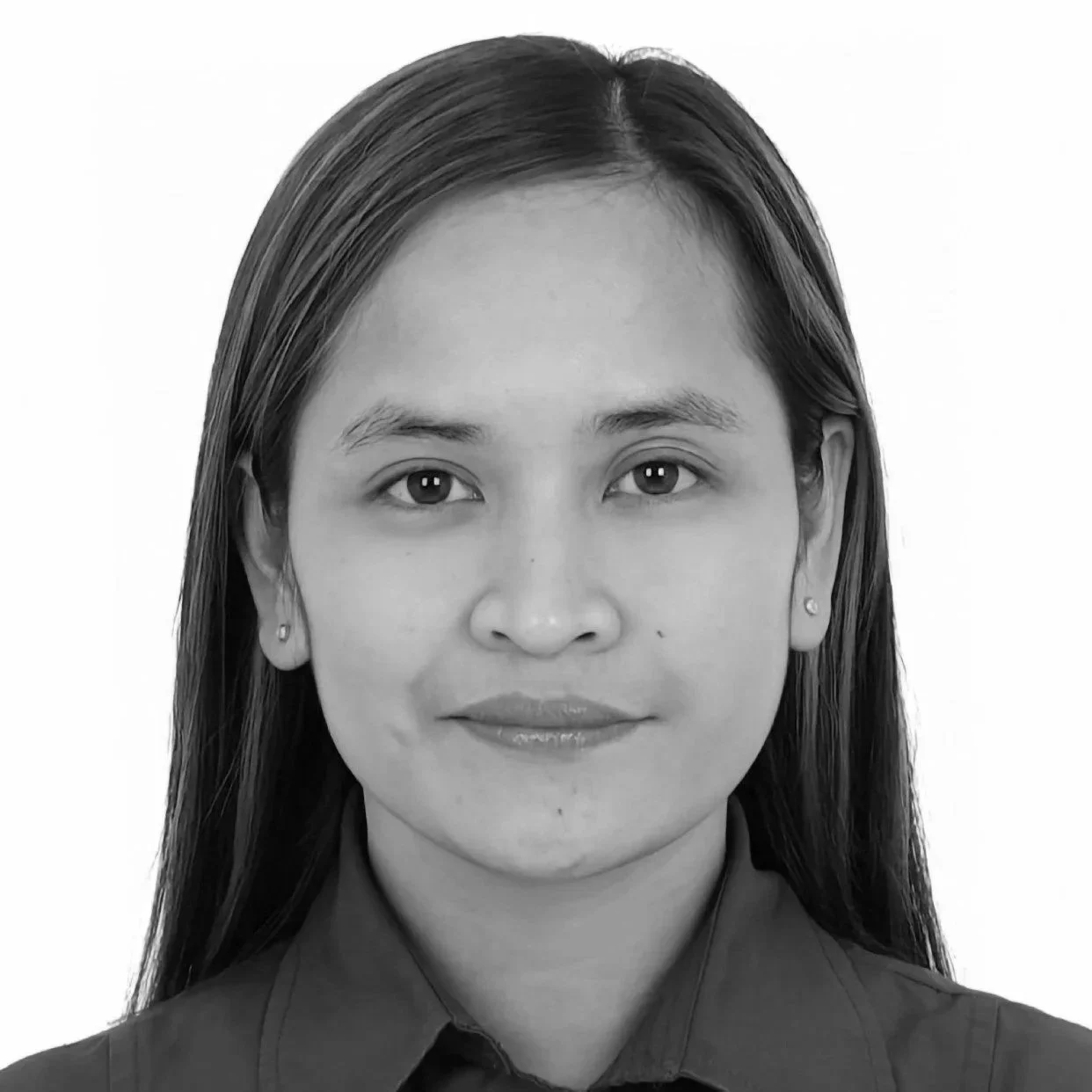 Close-up portrait of a young woman with light skin, brown eyes, and brown hair, wearing a gray collared shirt and small earrings, against a white background.