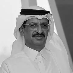 Portrait of a man wearing traditional Middle Eastern attire, including a white thobe and a black-and-white head covering, with glasses and a mustache.