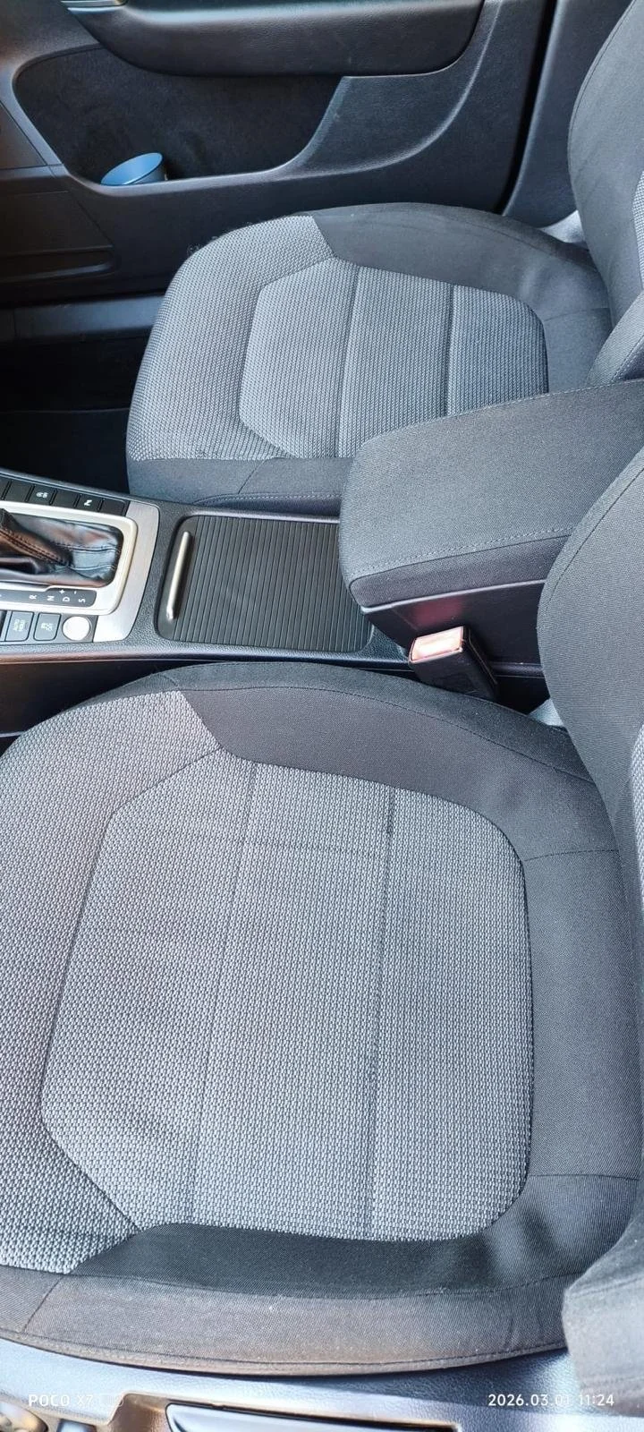 Interior of a car showing the front passenger seat, center console, and part of the driver’s seat with gray fabric upholstery.