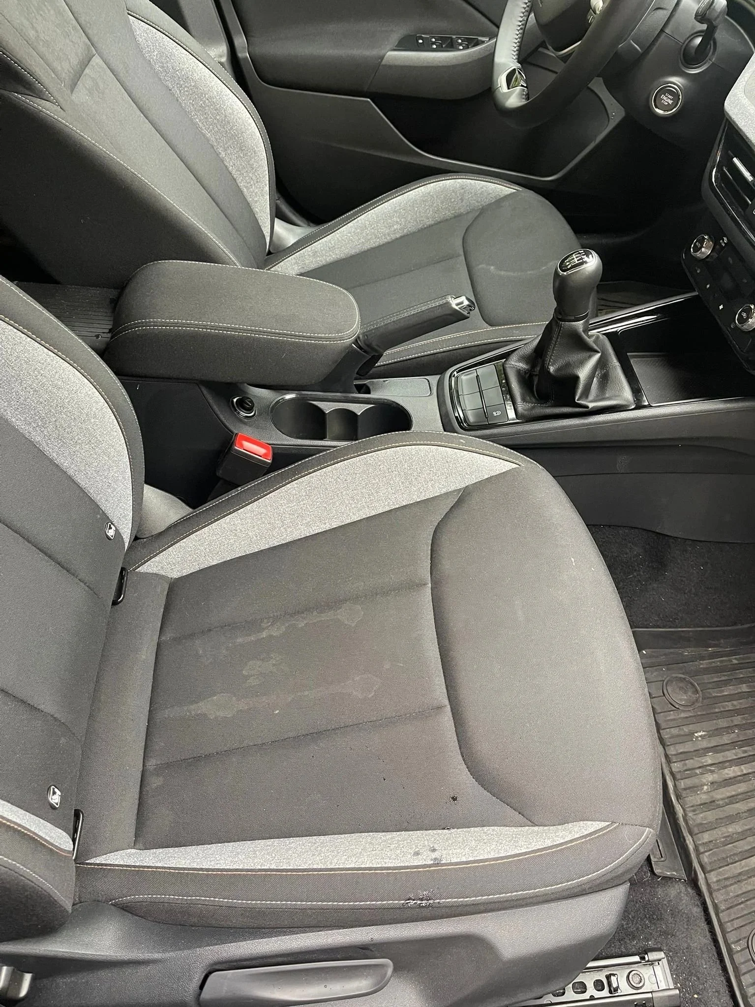 Unutrašnjost automobila sa suvozačkim sjedalom, mjenjačem i vidljivim mrljama na sjedalu