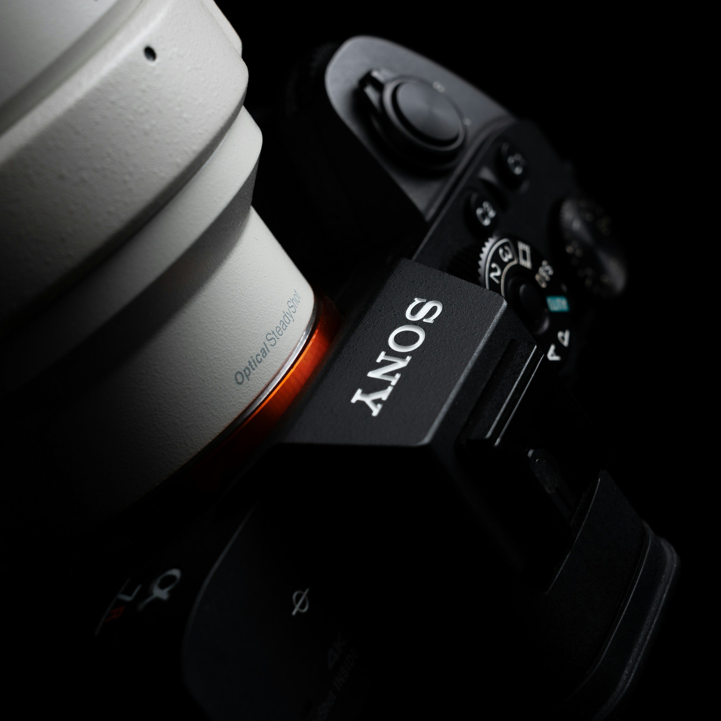 Close-up of a Sony camera with a large white lens and black camera body, with focus on the Sony logo on the camera.