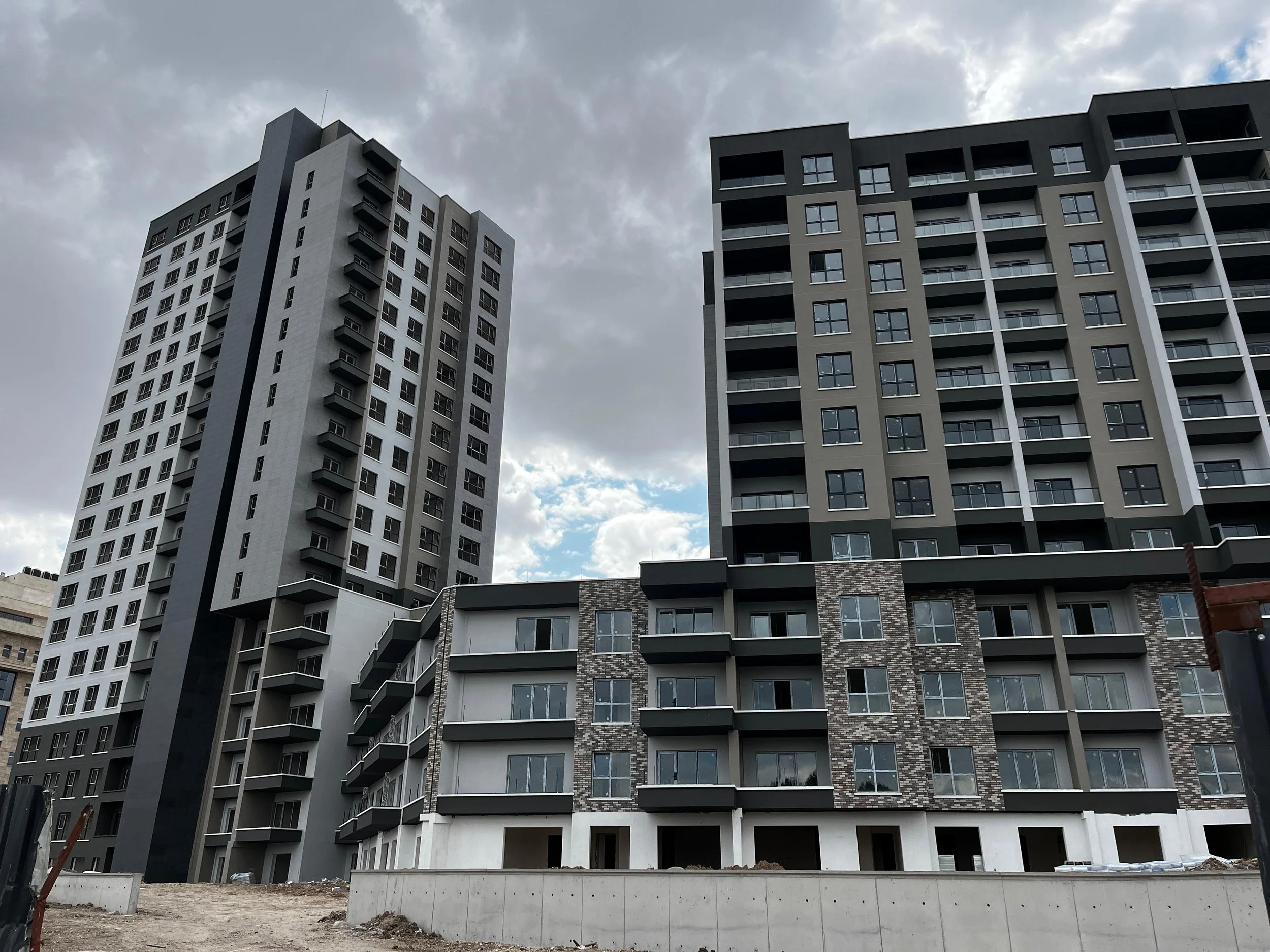 Multiple modern high-rise apartment buildings under a cloudy sky.