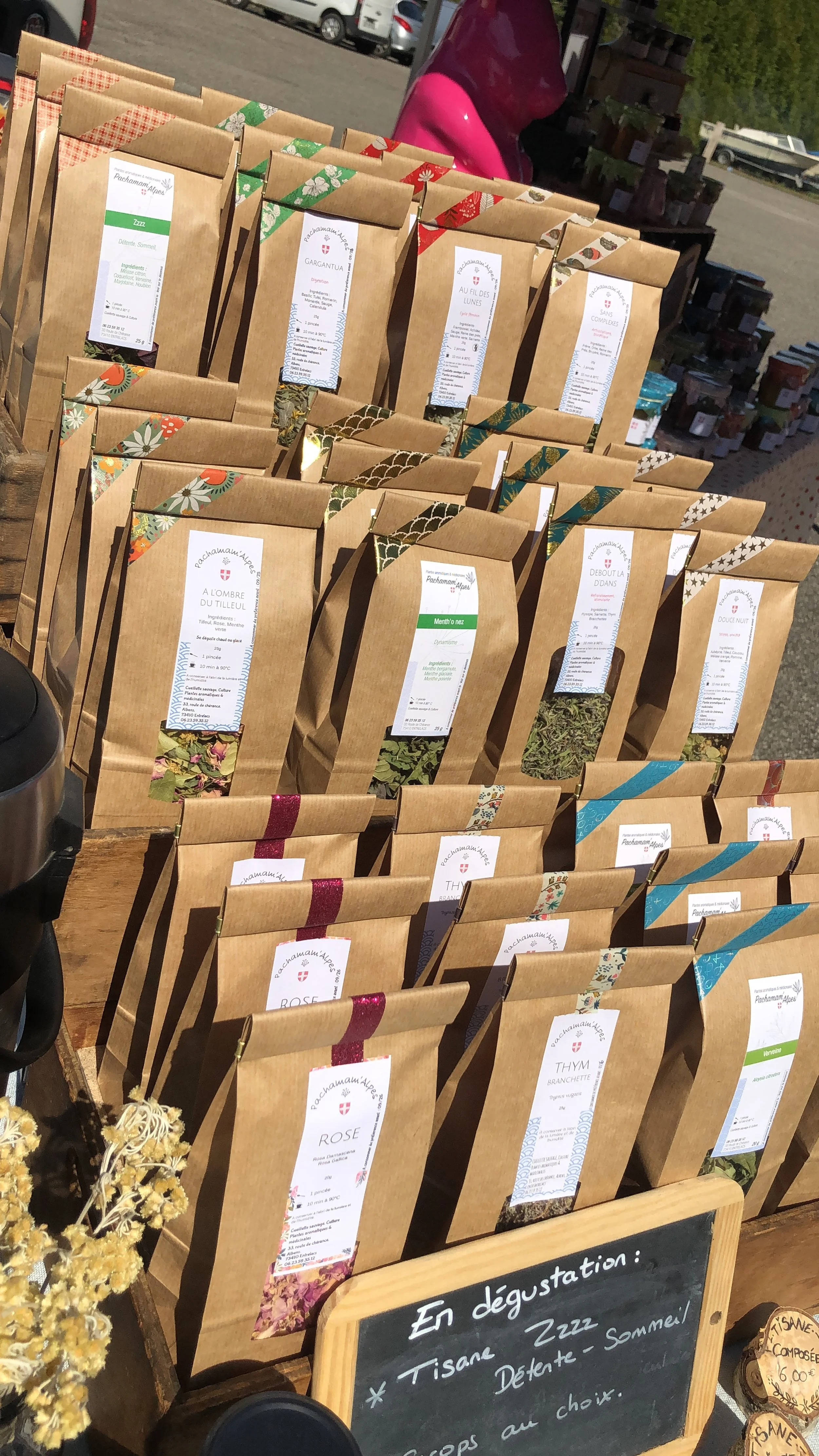 Paquets de thé en sachets en papier kraft avec des étiquettes colorées, exposés en magasin ou marché.