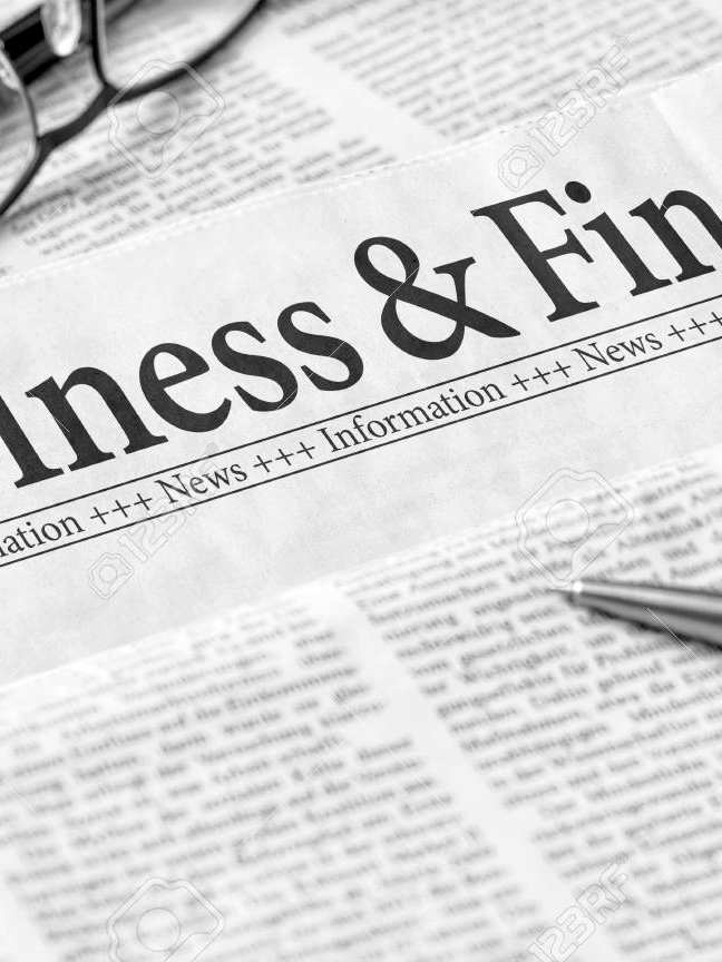 Close-up of a newspaper section titled 'Business & Fin' with a pen on the paper and eyeglasses in the background, and subheading 'News +++ Information +++ News'.