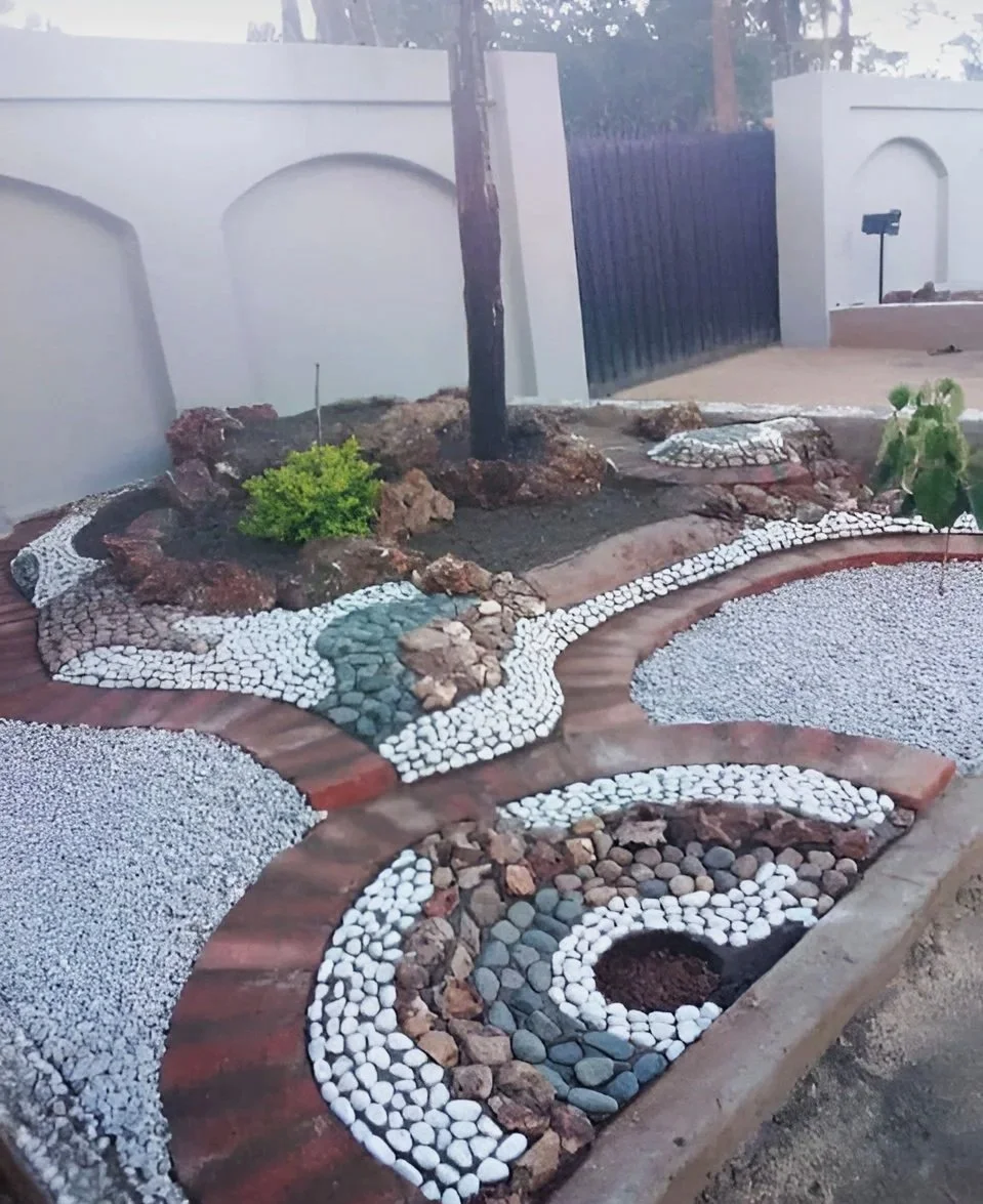 A backyard landscape with a white white pebbles, mixed pebbles and assortment of crushes.