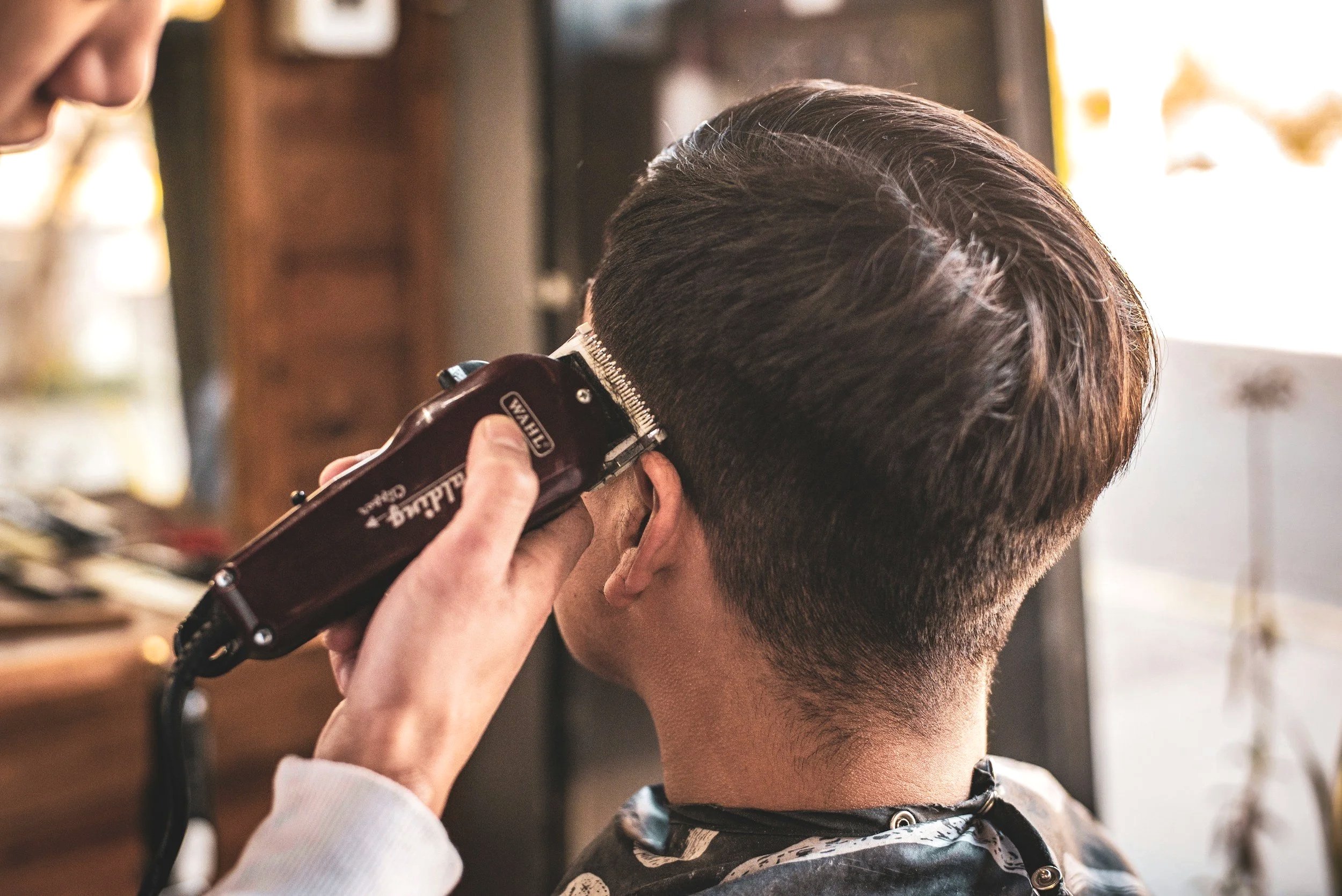 Hombre recibiendo un corte de cabello con máquina eléctrica en una barbería